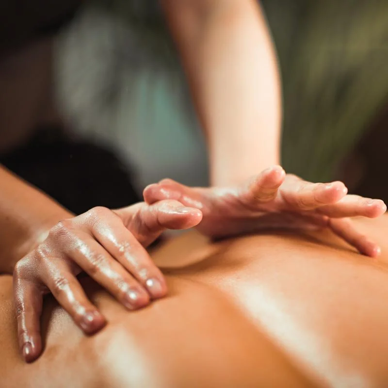 Close-up of hands giving a massage to a person's back.