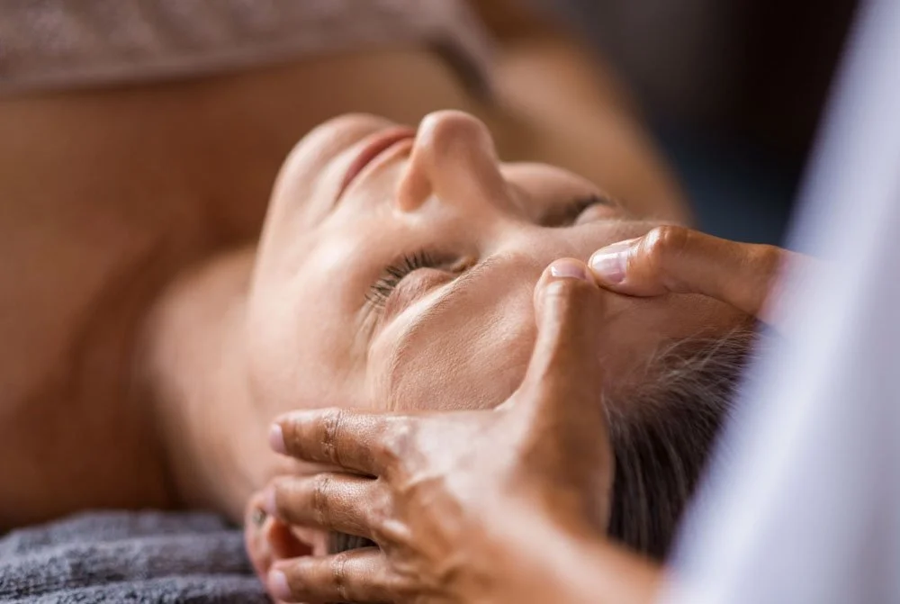 Person receiving a facial massage from a therapist.