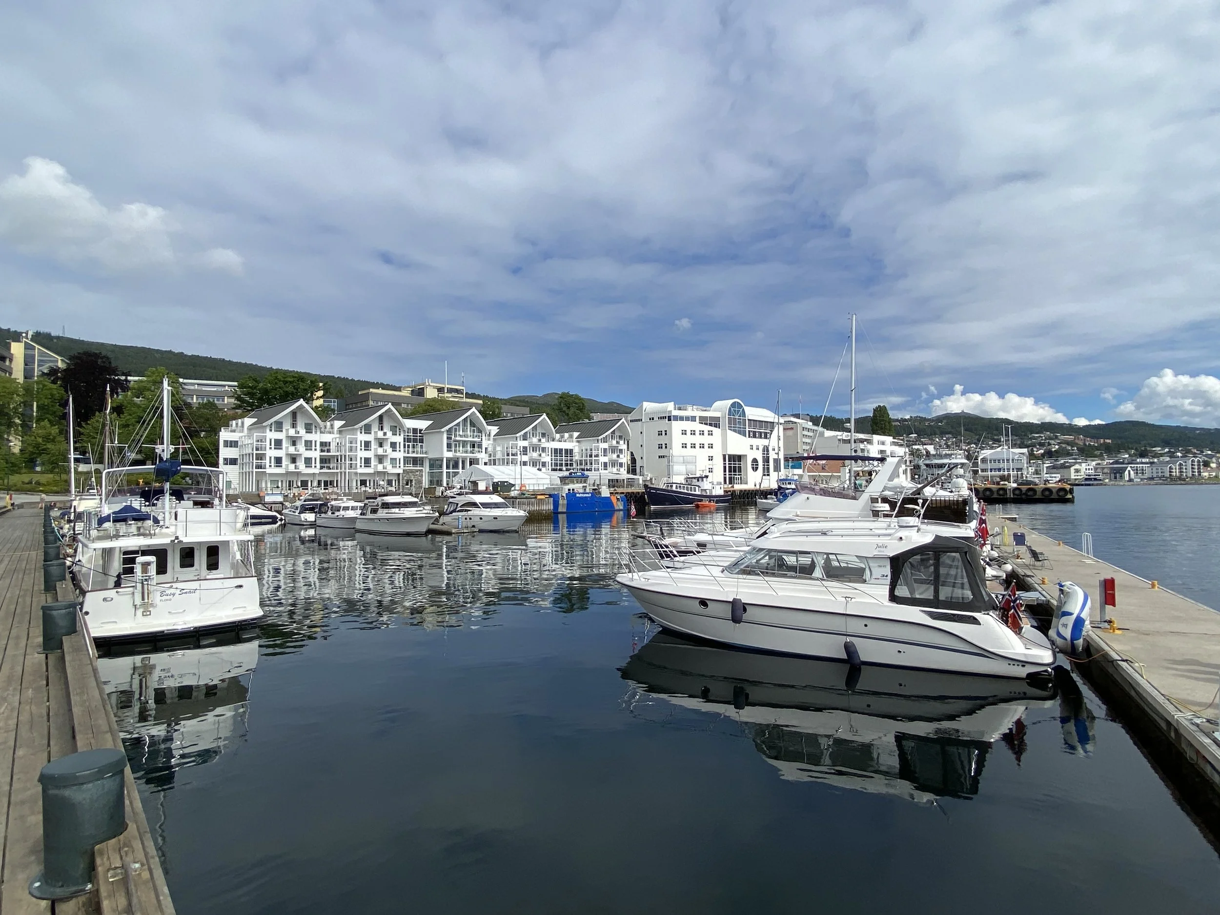 Gjestehavn i Molde. Båter i havnen med moderne bygninger og fjell i bakgrunnen under en overskyet himmel.