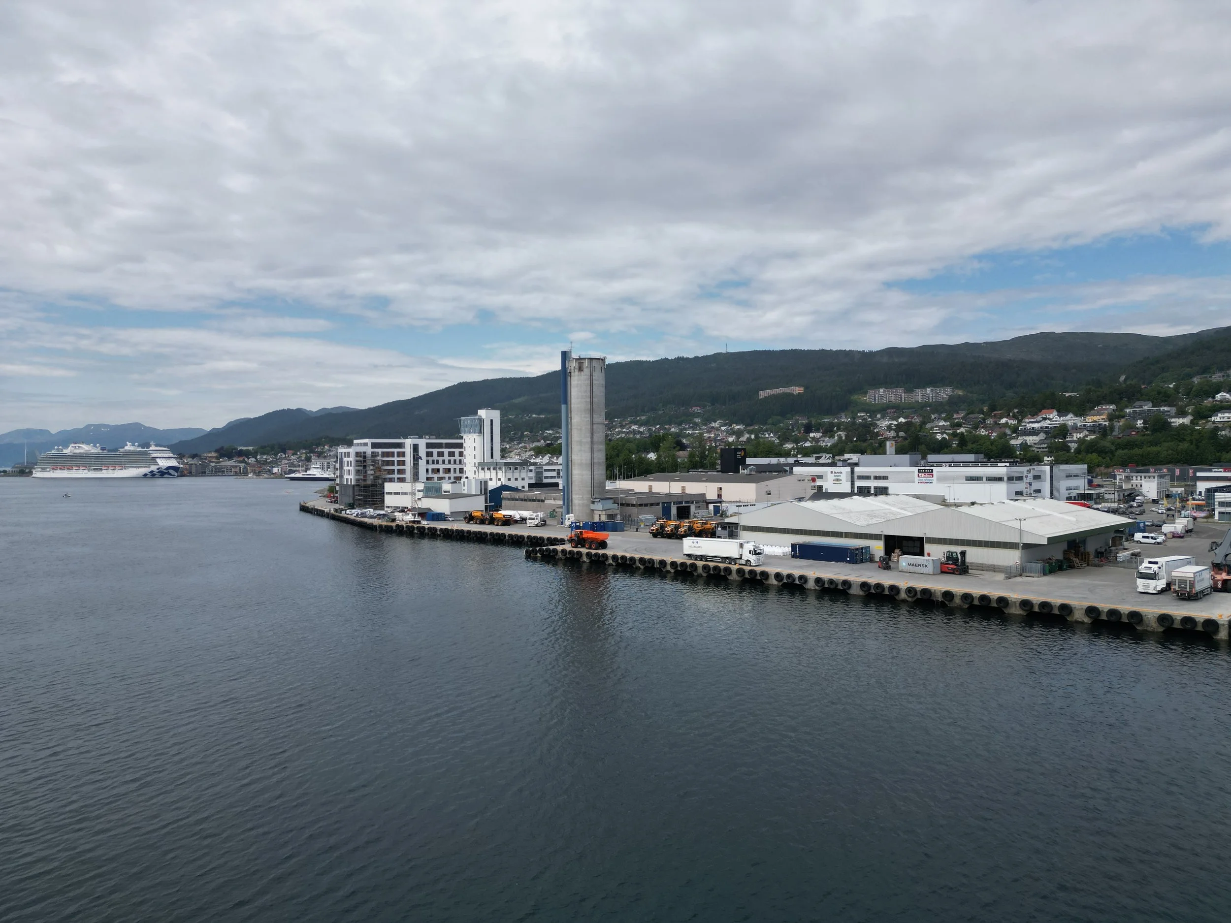 Moldegård (godshavn) i Molde. Utsikt over en havn med bygninger, båter og fjell i bakgrunnen, overskyet vær.