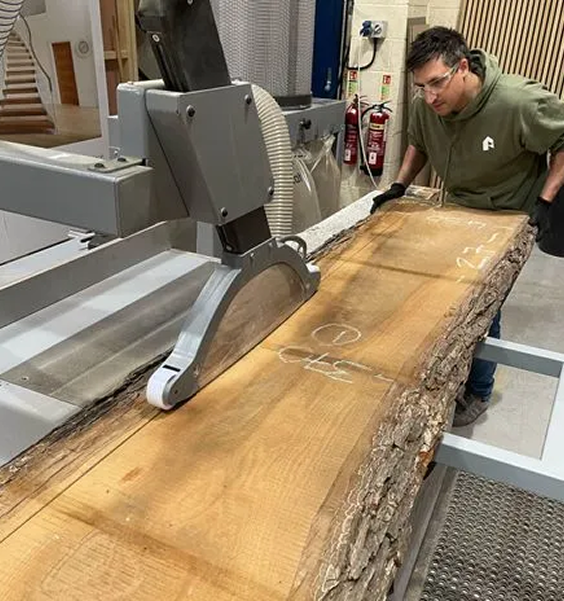 A worker working on lumber on an industrial rotary saw