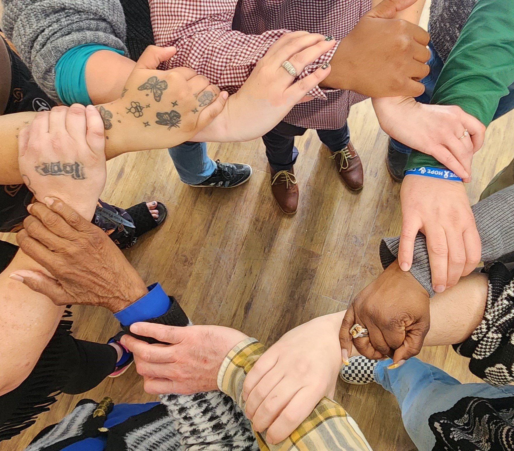 A group of diverse people in a circle, holding hands.