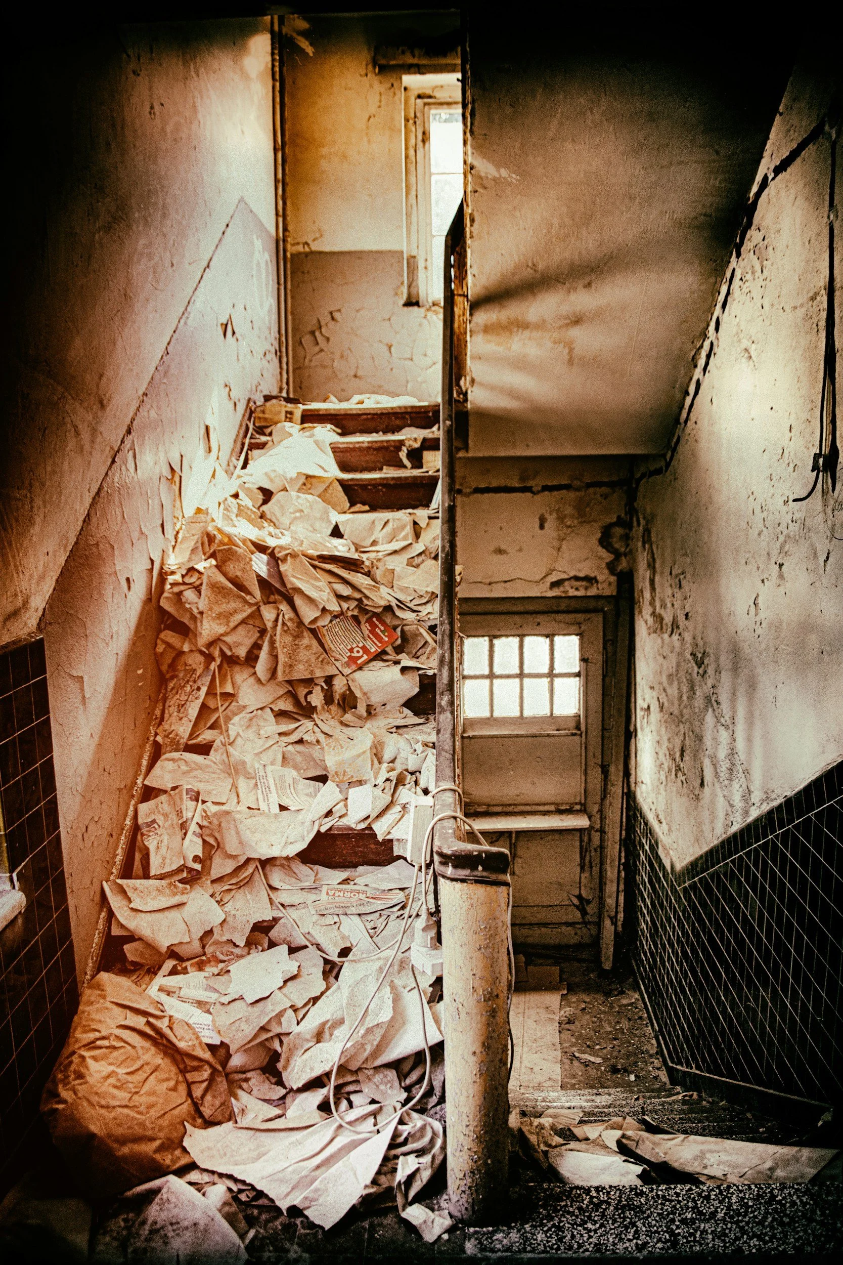 Hoarding cleanout before photo — entryway and staircase filled with trash and papers in a Minneapolis-St. Paul metro home served by Twin Cities Cleanouts