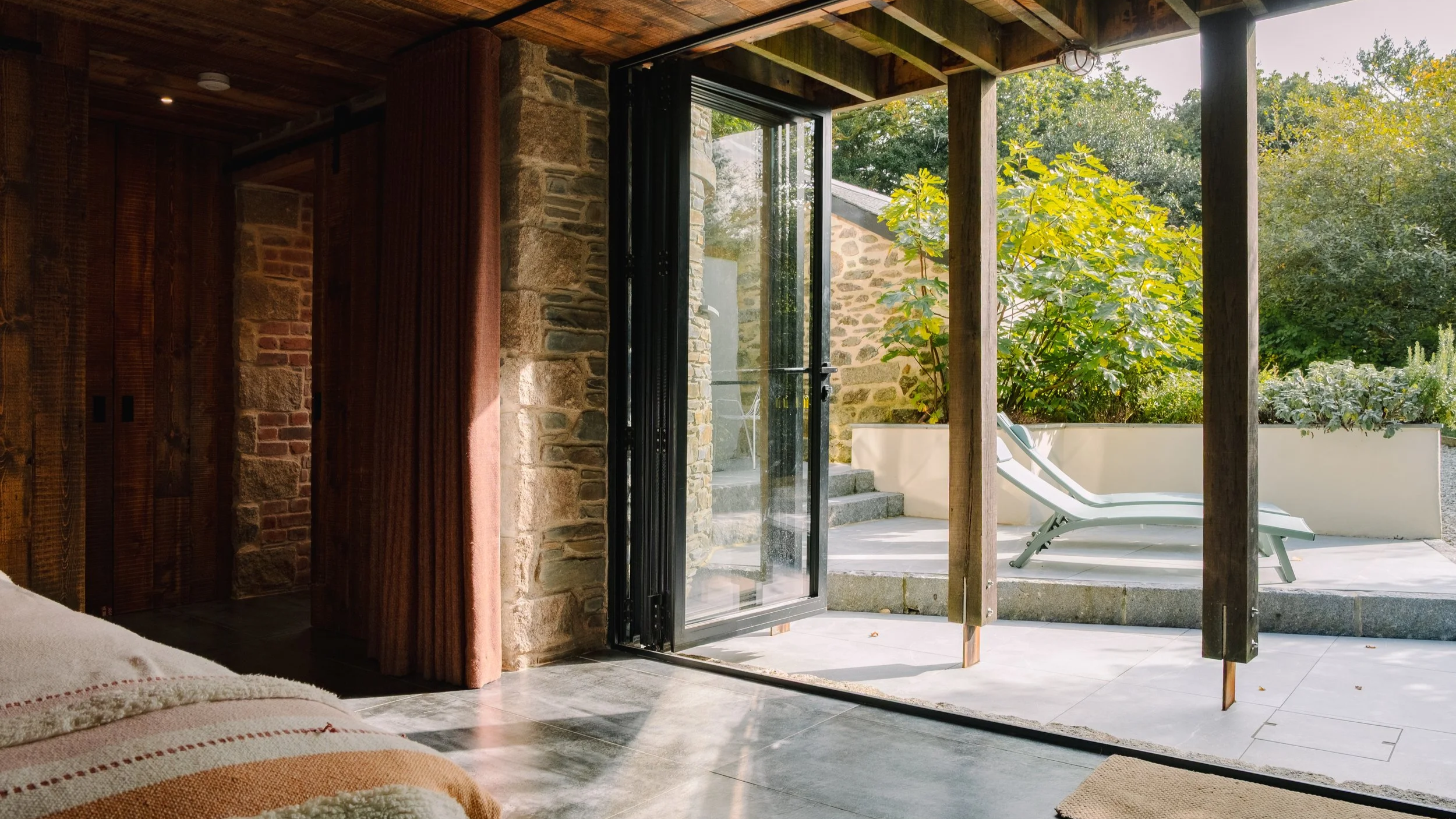 Full-height doors open the bedroom to the terrace, allowing light, air and nature to move effortlessly through the space.