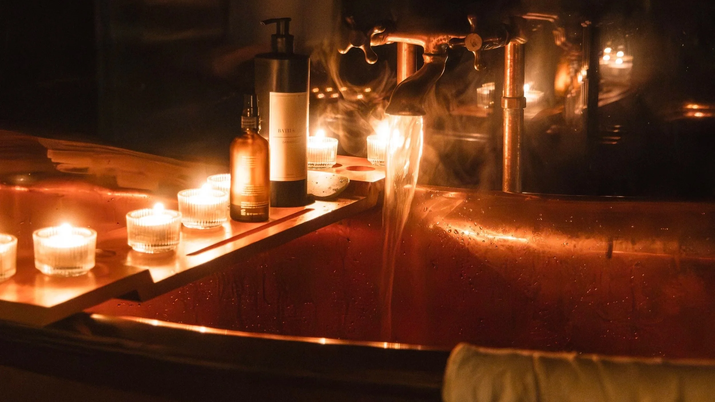 By night, the bathing space becomes a softly glowing sanctuary, where flickering candlelight and warm reflections set the scene for unhurried escape.