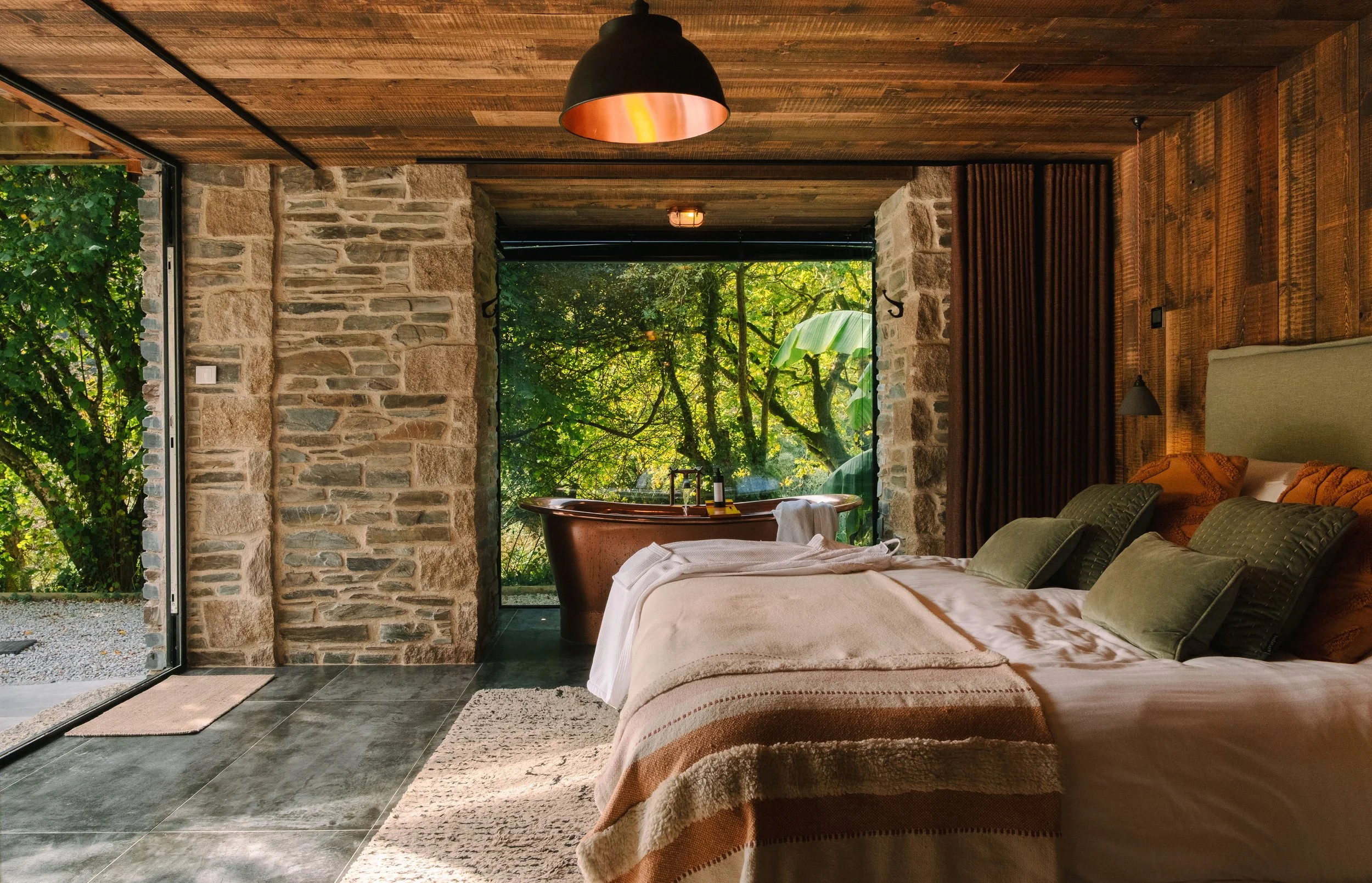 Wrapped in warm textures and natural light, the super-king downstairs bedroom offers a deeply restful retreat, with open doors framing tranquil woodland views and unhurried mornings beyond.