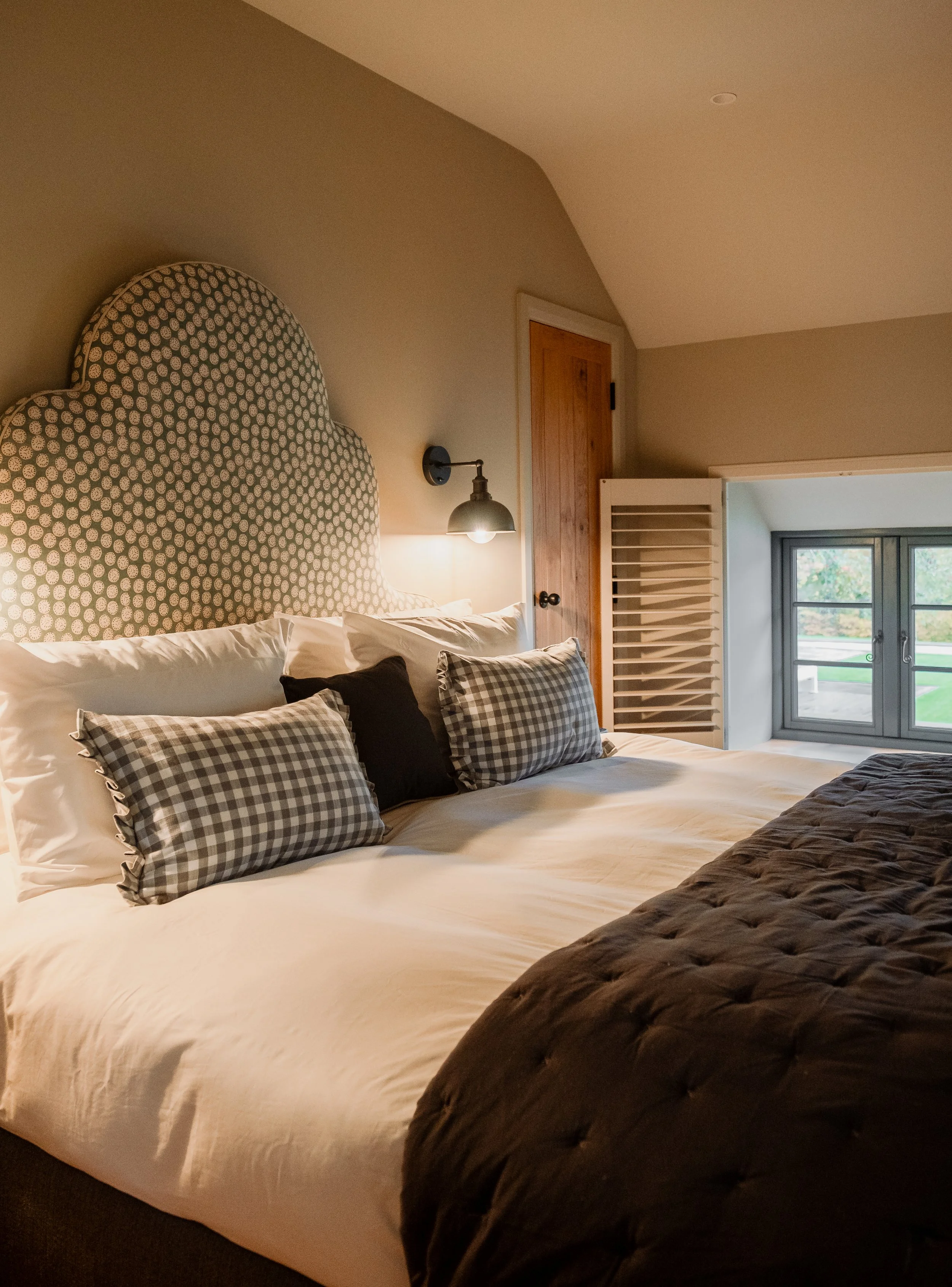 Upstairs, the first bedroom unfolds as a calm and beautifully layered retreat, where soft textures, muted tones, and gentle light create a space designed entirely for rest.