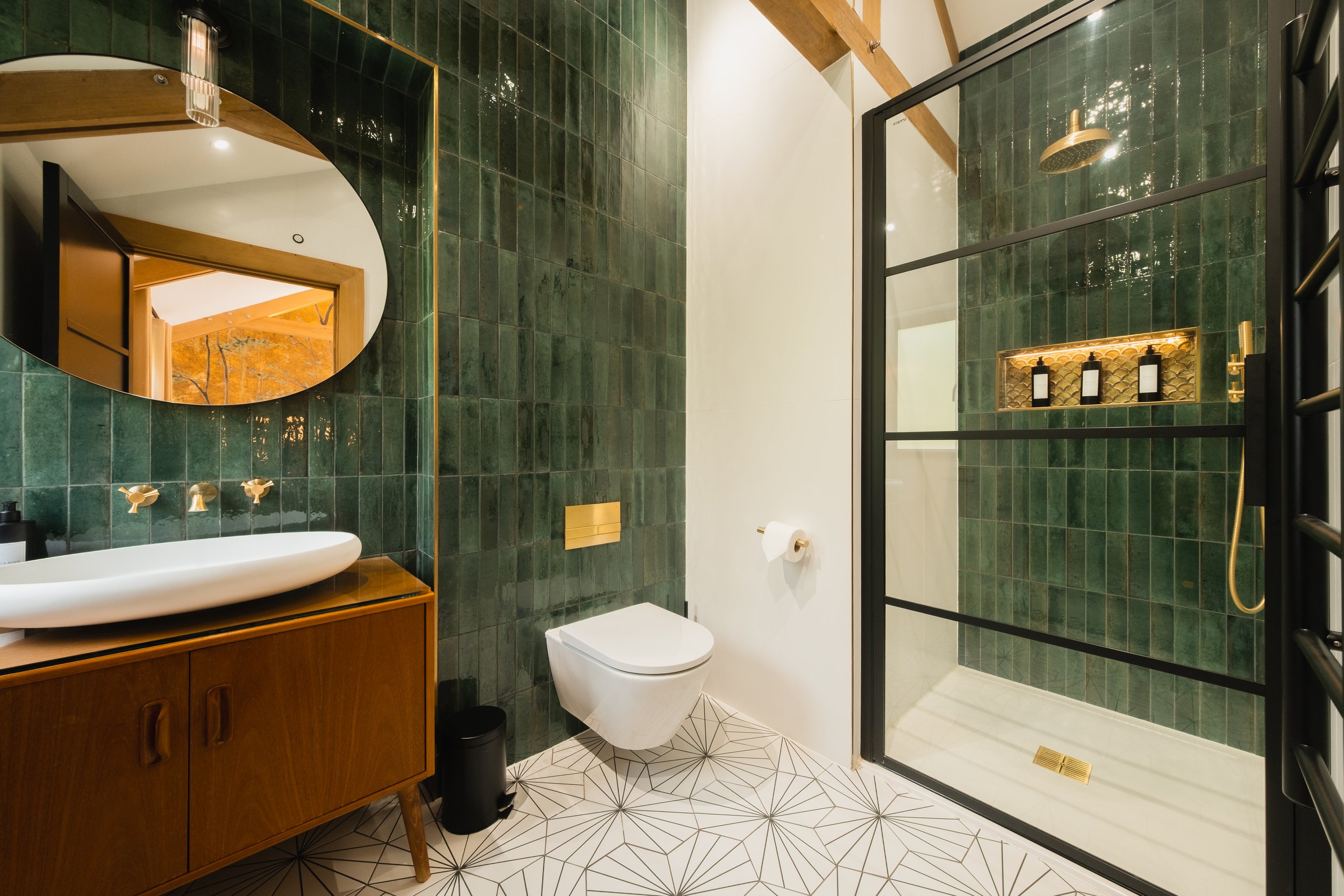 The ensuite blends deep green tones with warm textures, creating a space that feels both soothing and indulgent. From early mornings to evening unwinds, it is a place designed for calm and comfort.