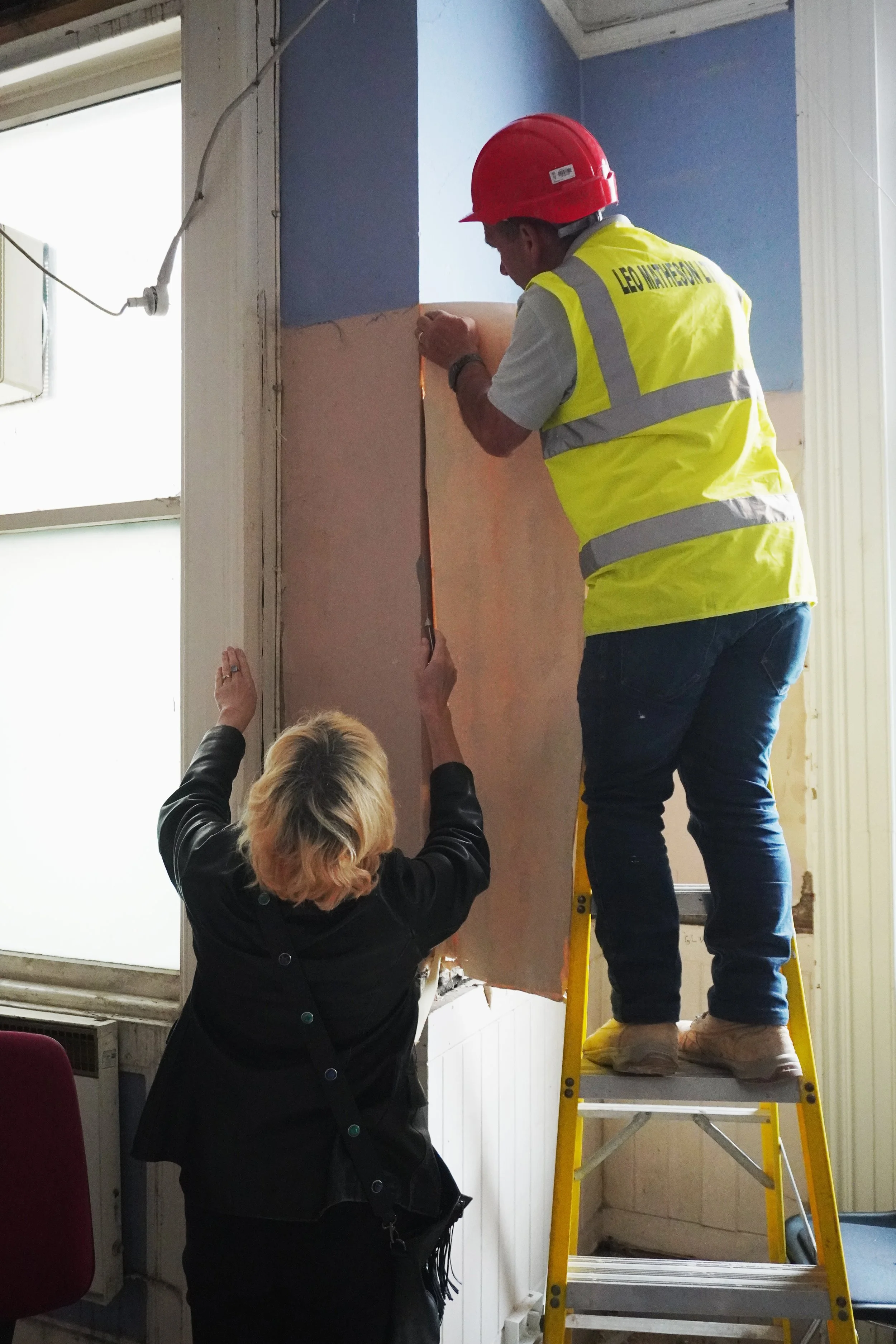 Alison and Victor carefully removing some of the original wallpaper for safekeeping 