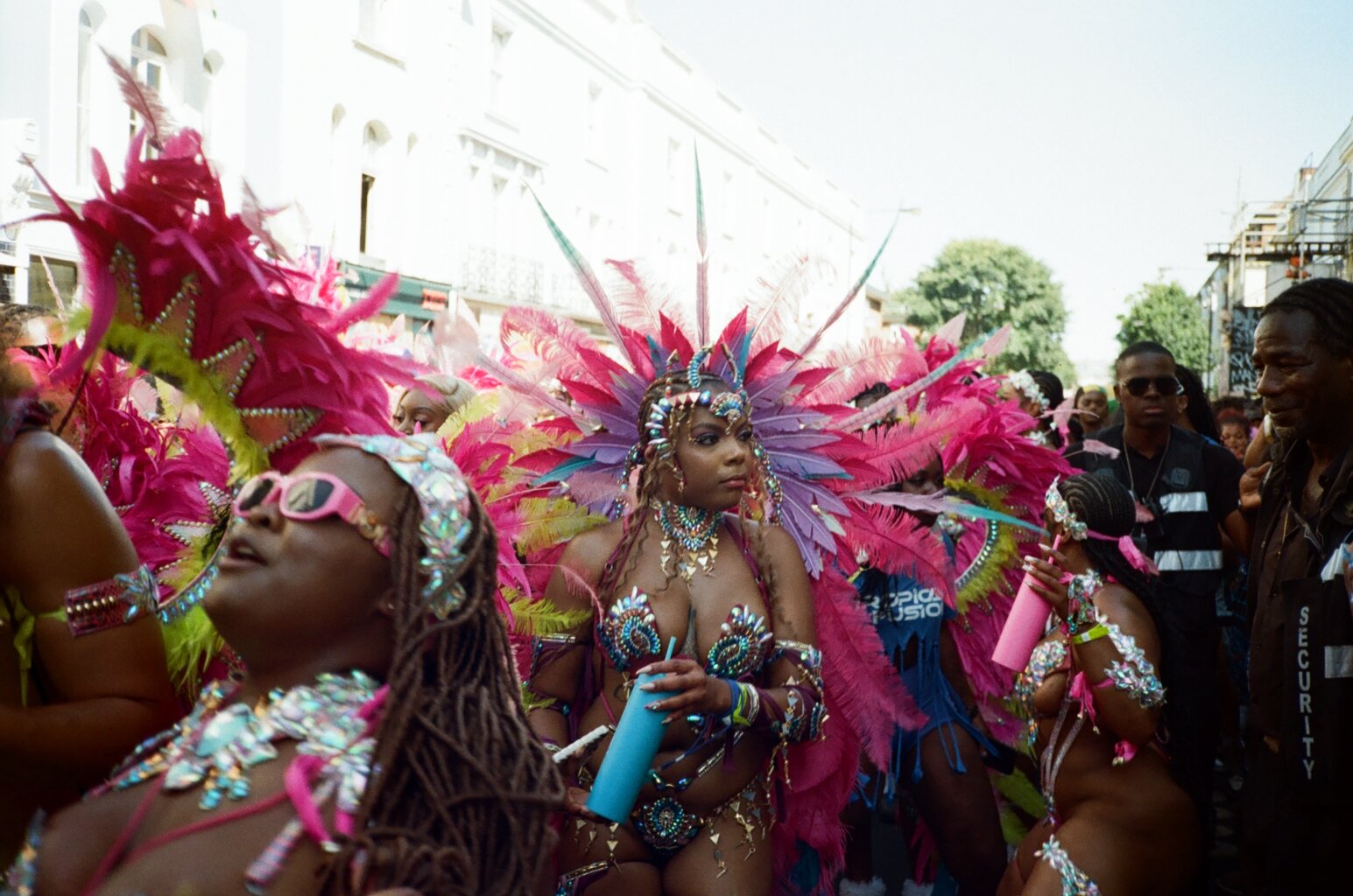 Women in colorful carnival costumes with feathers, beads, and face paint participating in a parade or festival.