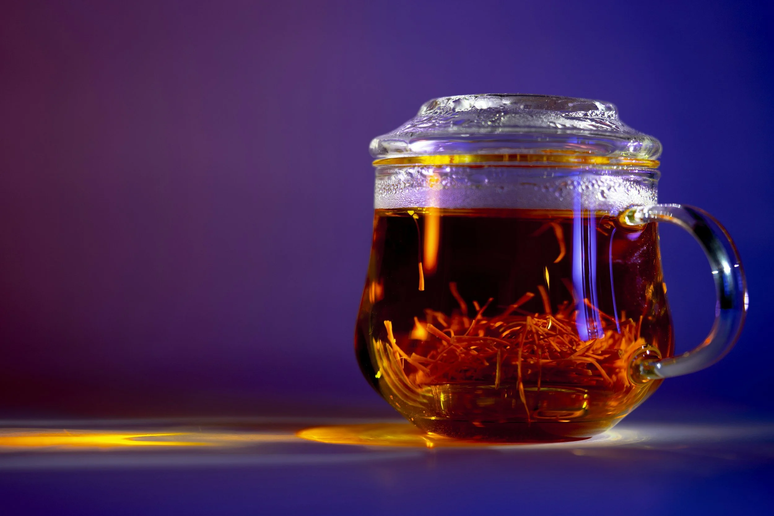 Close-up of a glass teapot filled with saffron tea.