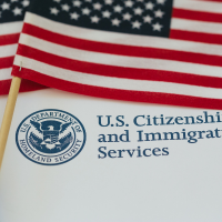 U.S. Citizenship and Immigration Services sign with American flag in the foreground.