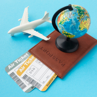 Travel essentials including a toy airplane, a globe, a passport, and airline tickets.