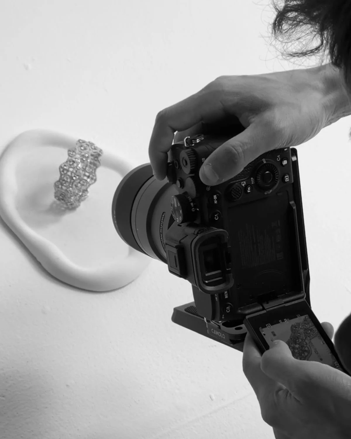 A person taking a photo of a white object with a camera, holding a phone in their other hand.