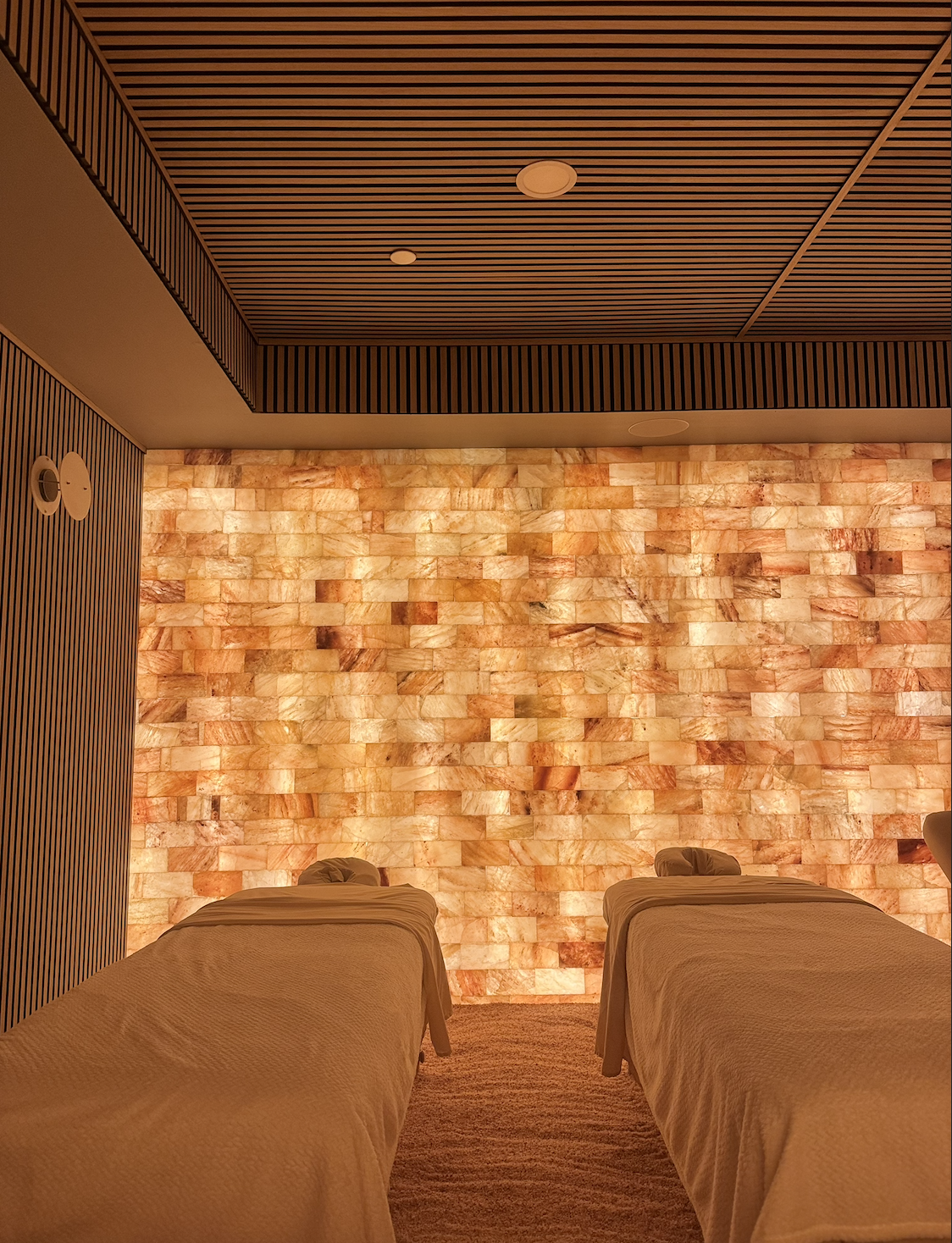 Spa room with two massage beds and a glowing salt wall.