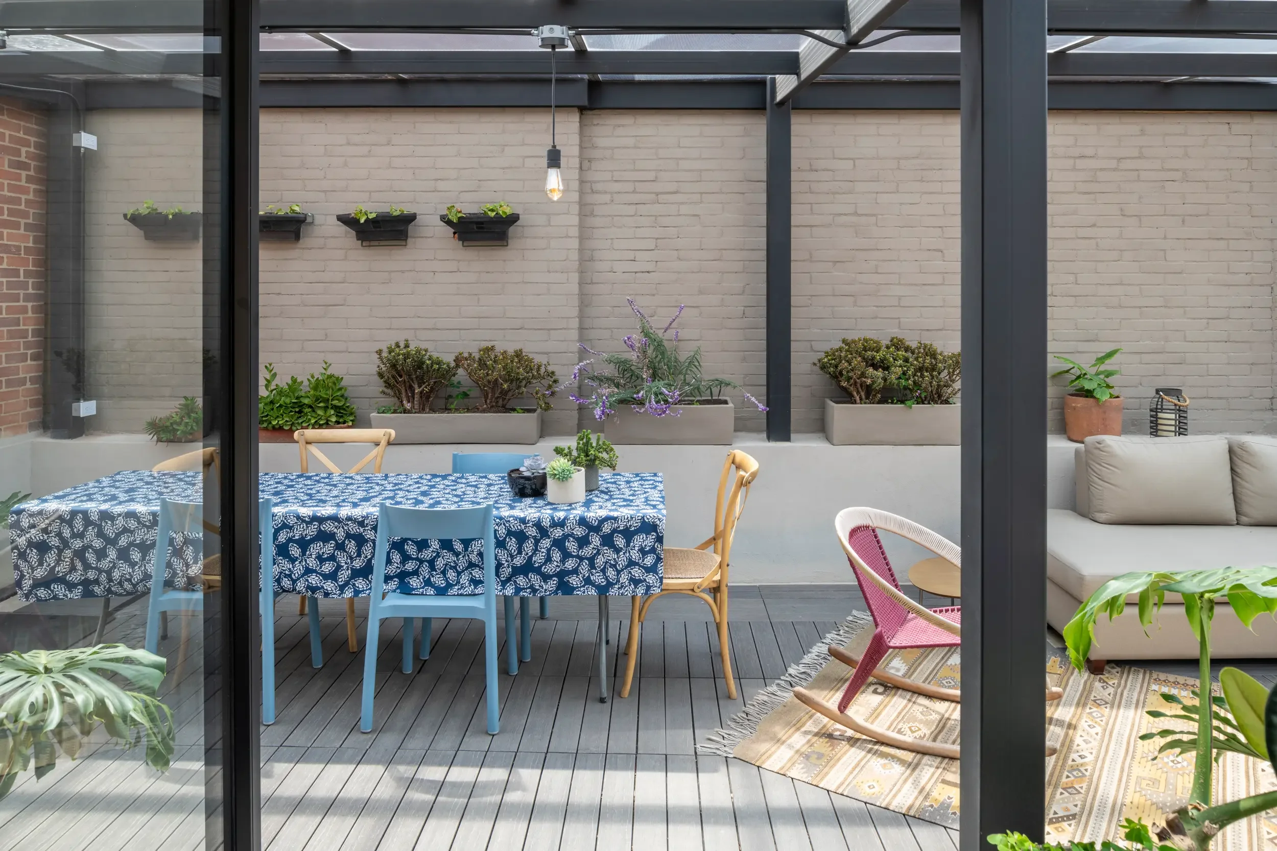 Minimalist terrace in Bogotá apartment renovation, accessible via new staircase, providing a quiet outdoor endpoint to the compact living space journey