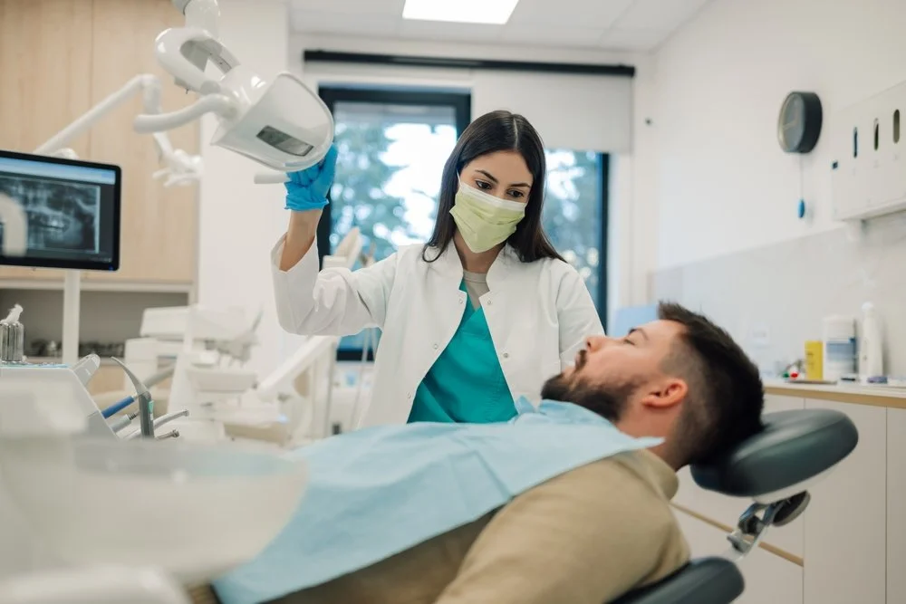 Dentist wearing a mask and blue gloves working on a patient in a dental clinic