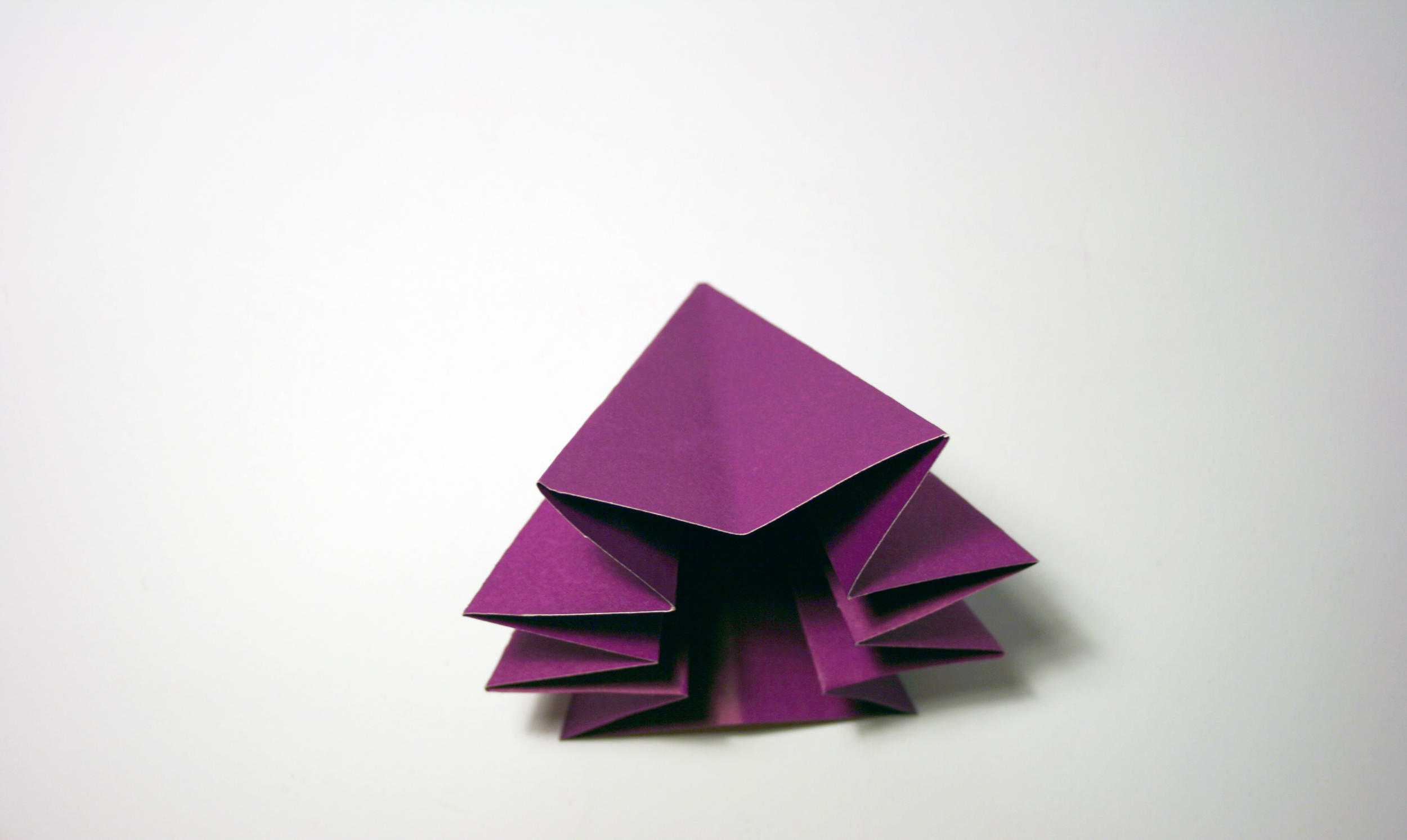 A purple origami creation resembling a star sits on a white background