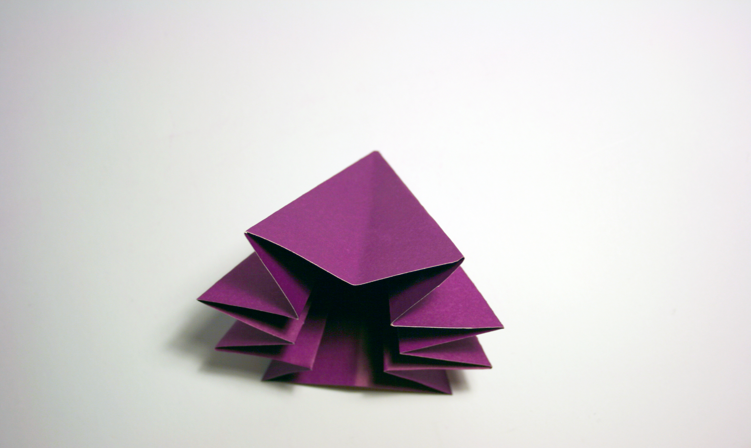 A purple origami creation resembling a star sits on a white background
