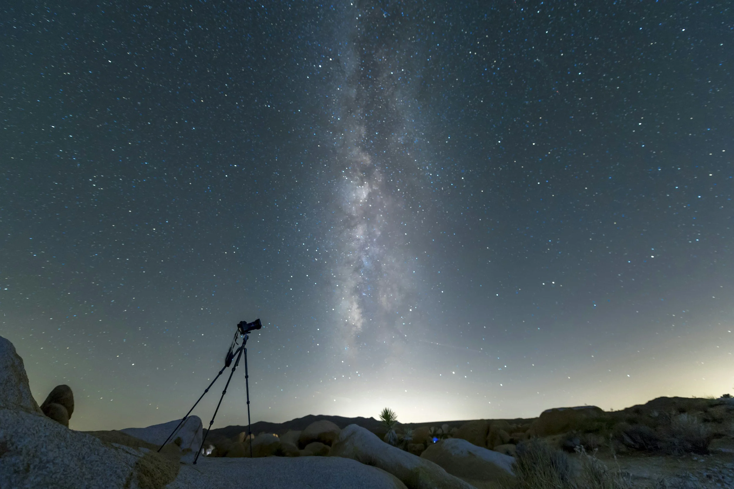 Night sky filled with stars and the Milky Way galaxy, with a telescope searching for larger stars