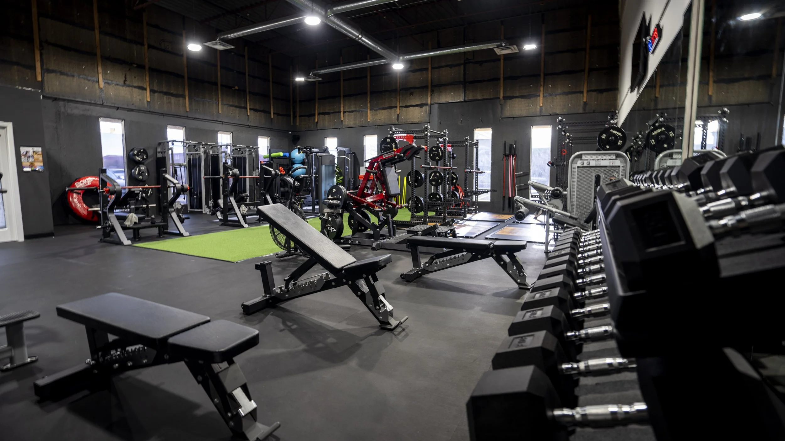 Interior of a well-equipped gym with various fitness machines, free weights, and workout benches.