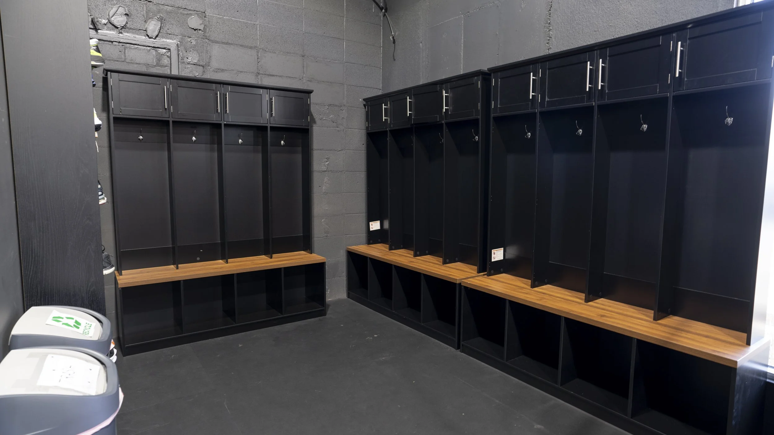 Empty black lockers with wooden benches inside a gym or locker room