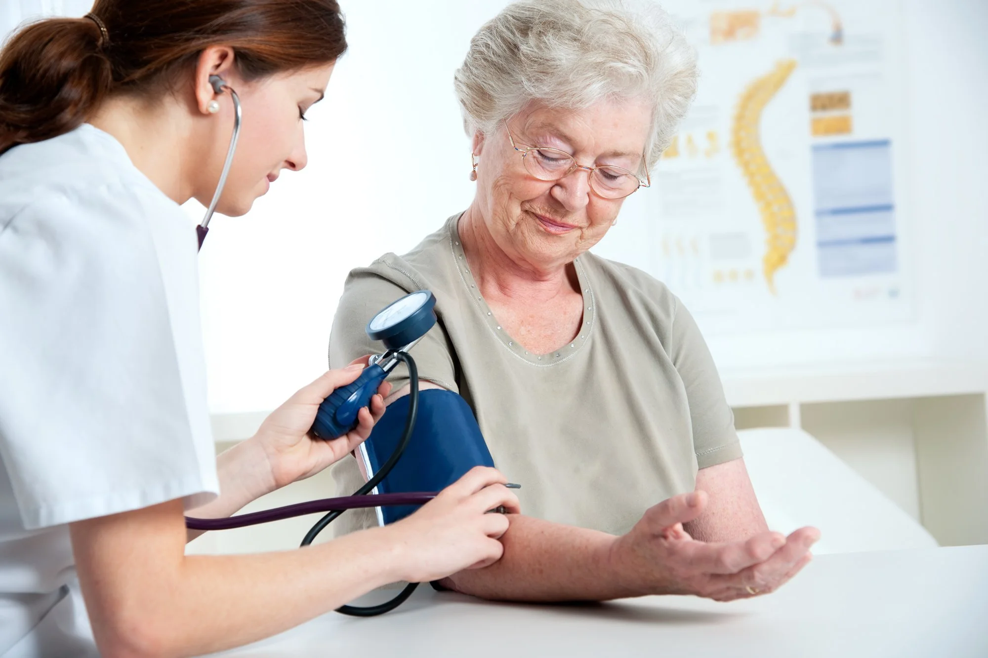 A healthcare professional measuring an elderly woman's blood pressure with a sphygmomanometer.