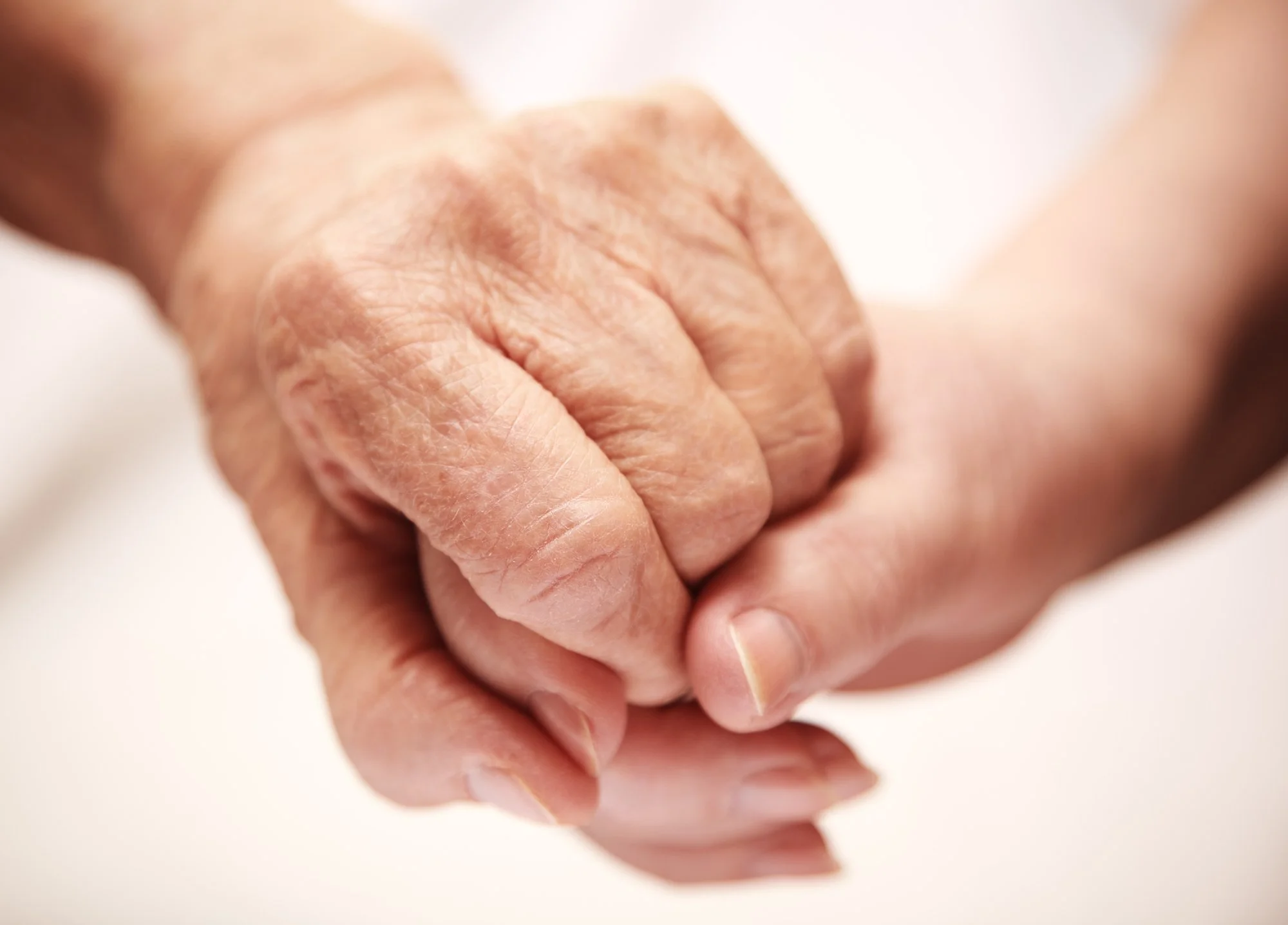 Close-up of an elderly person's hand with visible age spots, lightly clenched.