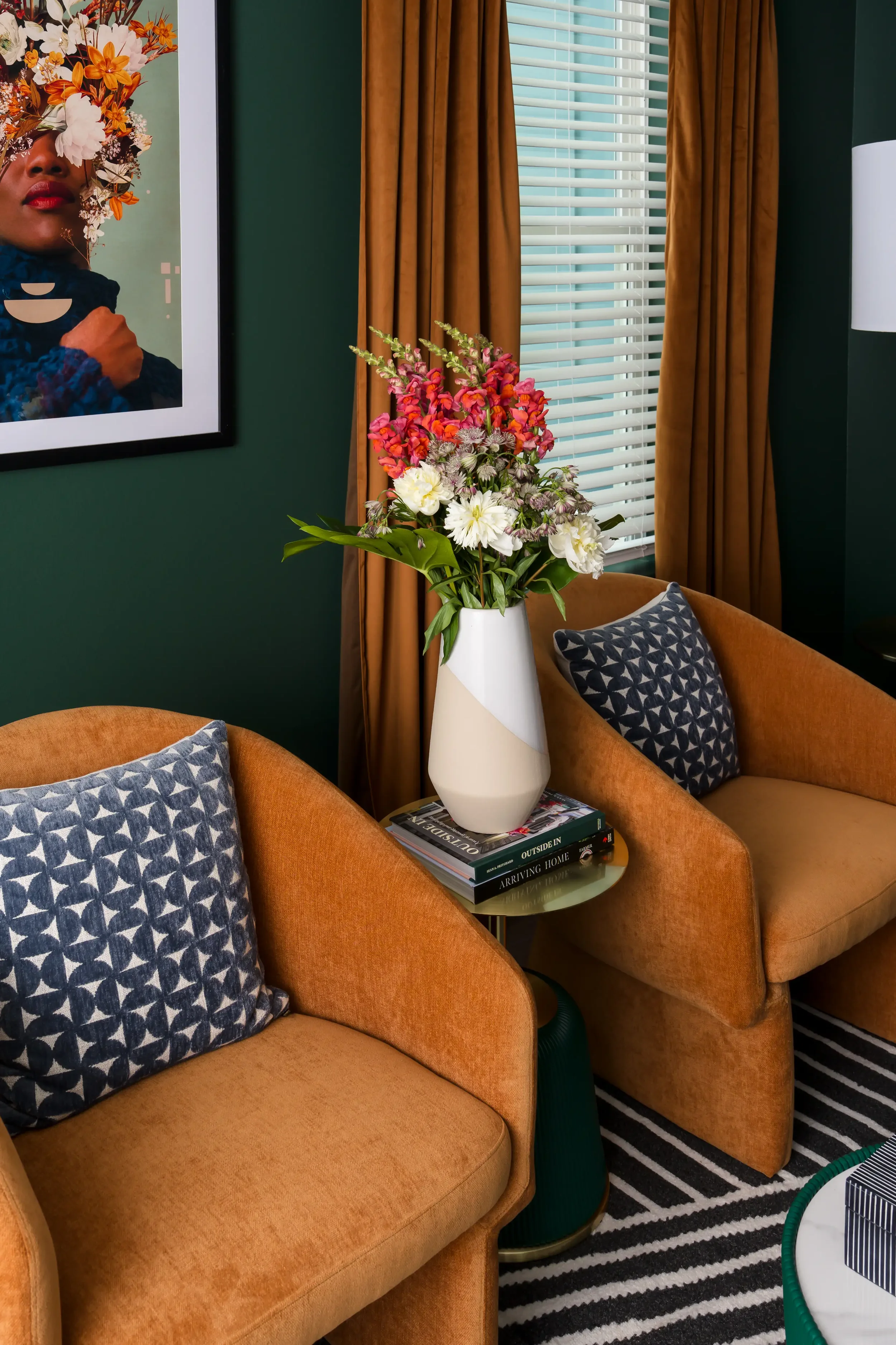 Amenity lounge seating nook at East 9th in Dallas, TX, featuring cognac velvet armchairs, mustard drapes, green walls, and a striped rug, designed by Artbuckle & Co.