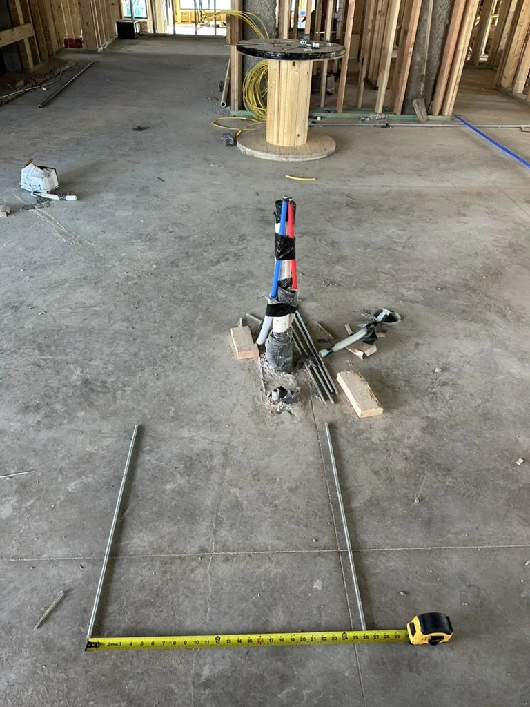 Raw concrete slab layout and utility conduit measurement during early framing phase for Beacon in Frisco, Texas, managed by Artbuckle & Co.