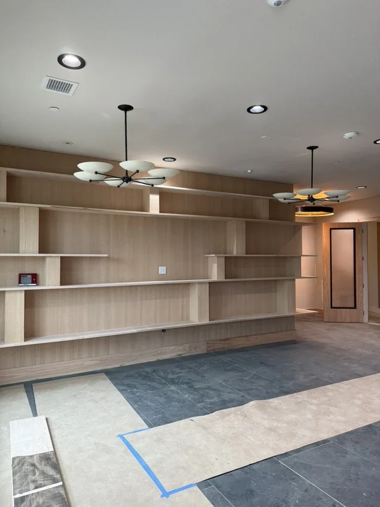 Before: unfinished amenity room at The View in Frisco's Rail District with raw oak shelving and slate floor tile.