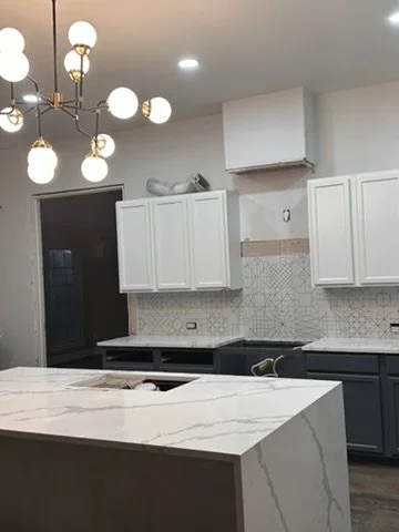 Active installation of a brass globe chandelier, white quartz waterfall island, and grey cabinets in a Sunnyvale, TX home, by Artbuckle & Co.