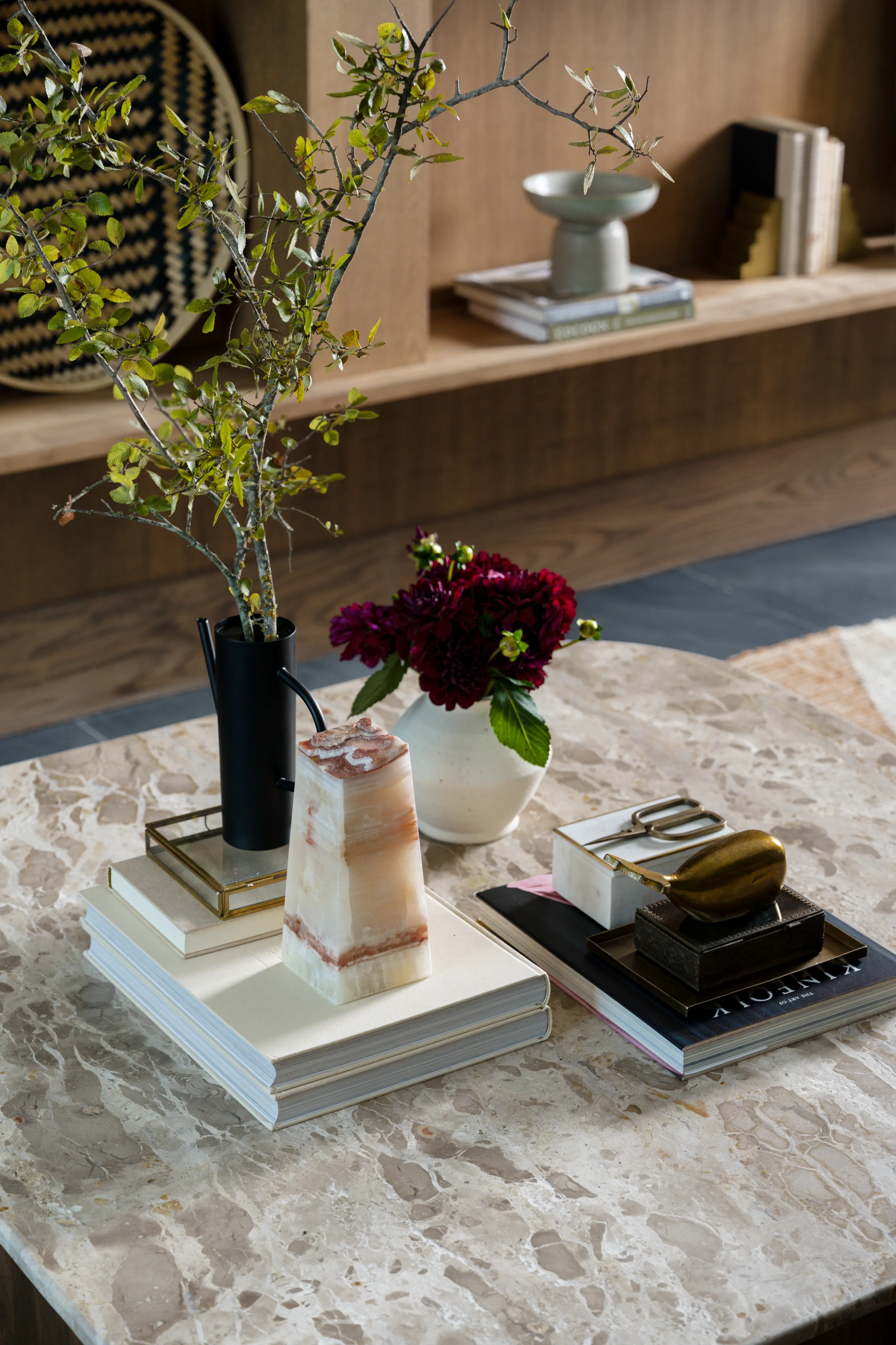 Styled marble coffee table with dark dahlias, an onyx obelisk, and stacked books at The View in Frisco, Texas, designed by Artbuckle & Co.
