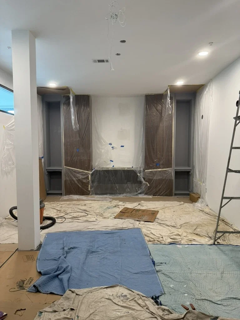 Lounge TV wall in progress at The Platform in Frisco, TX with fluted walnut panels and built-ins. Designed by Artbuckle & Co. Built by MC Cabinet Co.