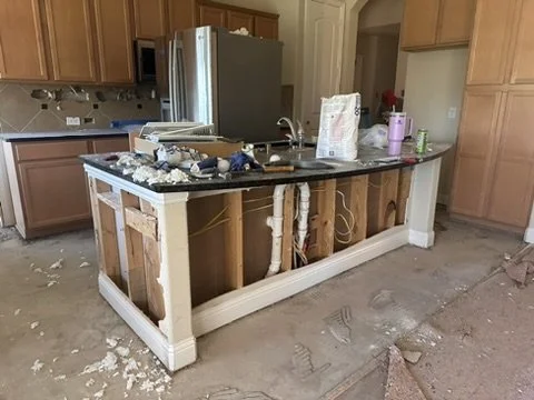 Exposed island plumbing rough-in and framing phase during a custom luxury kitchen buildout in Sunnyvale, TX, by Artbuckle & Co.