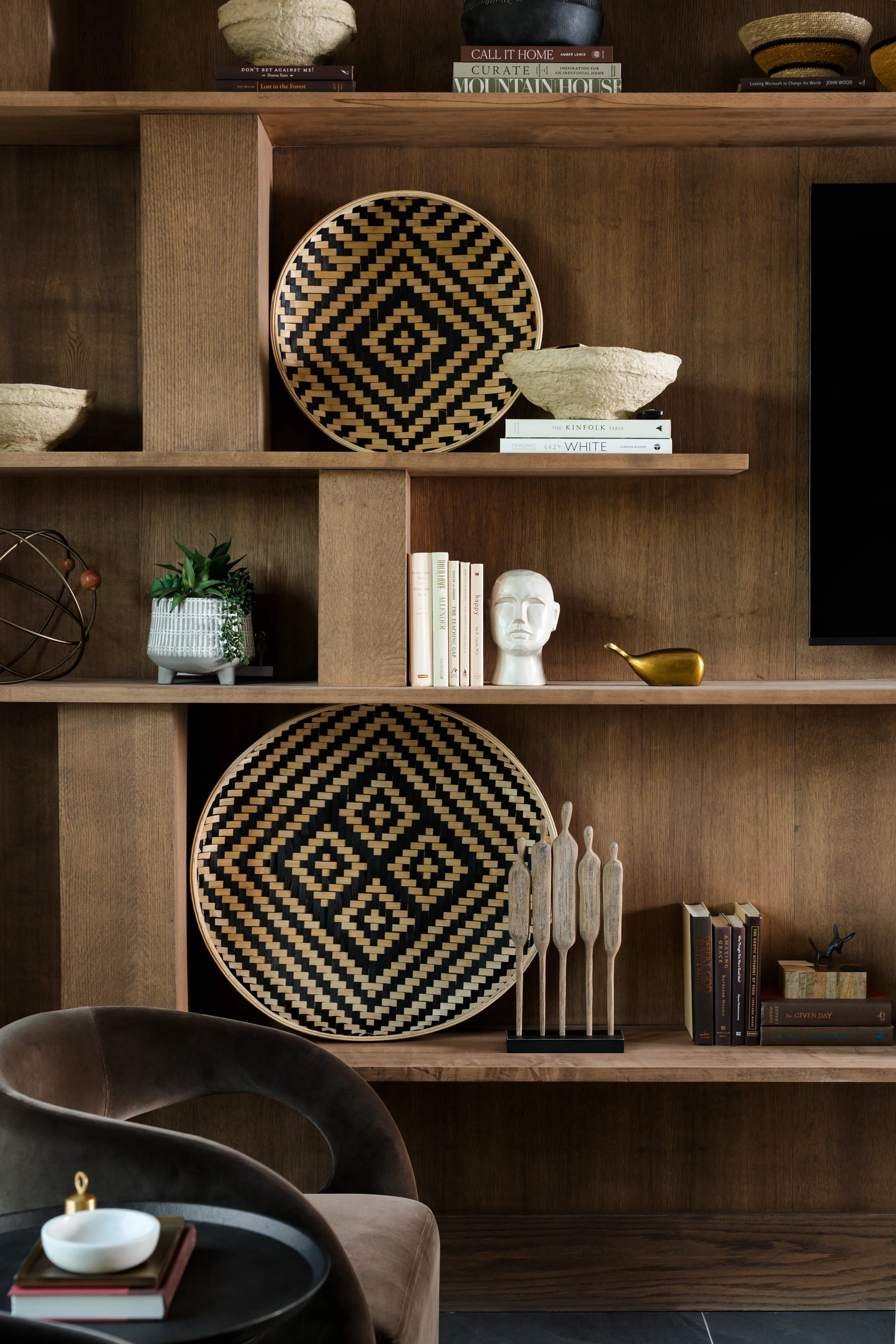 Custom walnut shelving styled with woven baskets, sculpture, and books at The View in Frisco, Texas, designed by Artbuckle & Co.