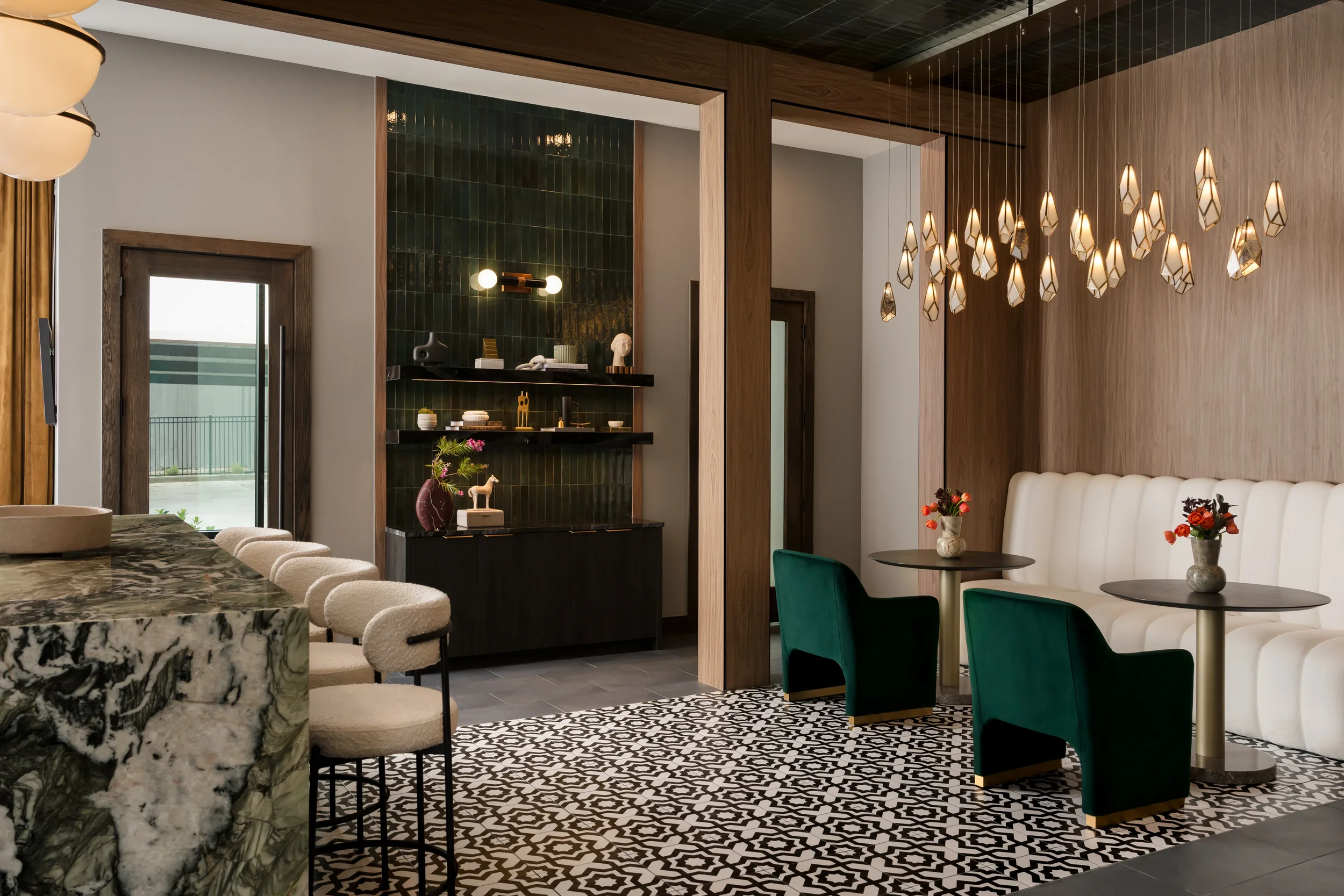 Amenity lounge with a marble bar, green tile shelving, and a tufted banquette, designed by Artbuckle & Co.