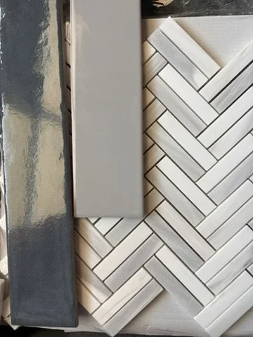 Tile selection flat-lay featuring grey subway tile in a herringbone pattern and geometric backsplash samples for a Sunnyvale, TX home, by Artbuckle & Co.