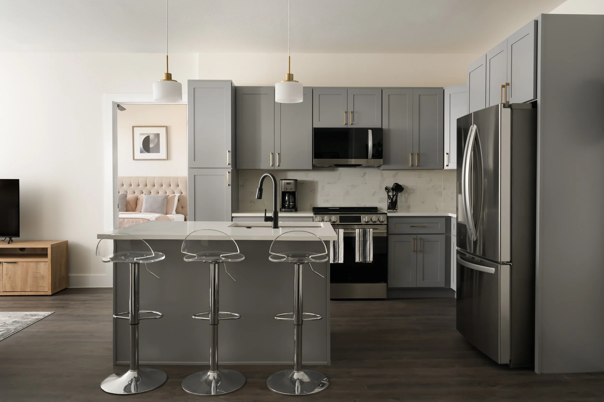 Apartment kitchen at The View in Frisco's Rail District with gray shaker cabinets and acrylic bar stools. Designed by Artbuckle & Co.