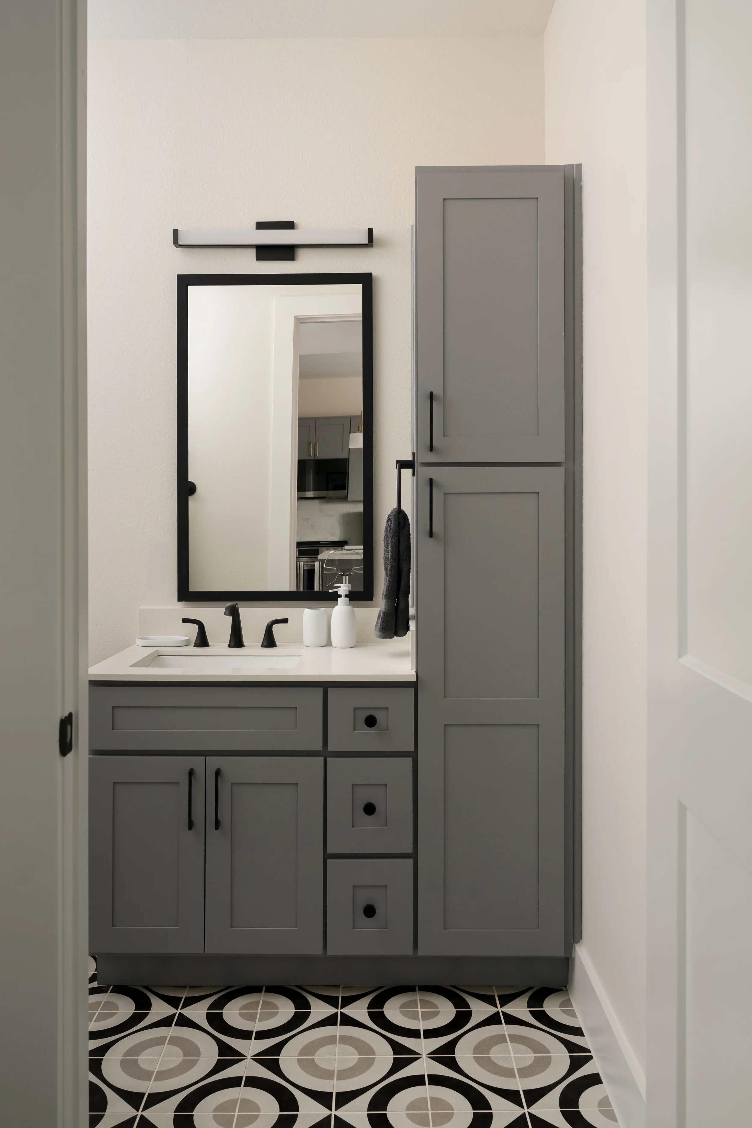 Apartment bathroom at The View in Frisco's Rail District with gray vanity and black-and-white tile floor. Designed by Artbuckle & Co.
