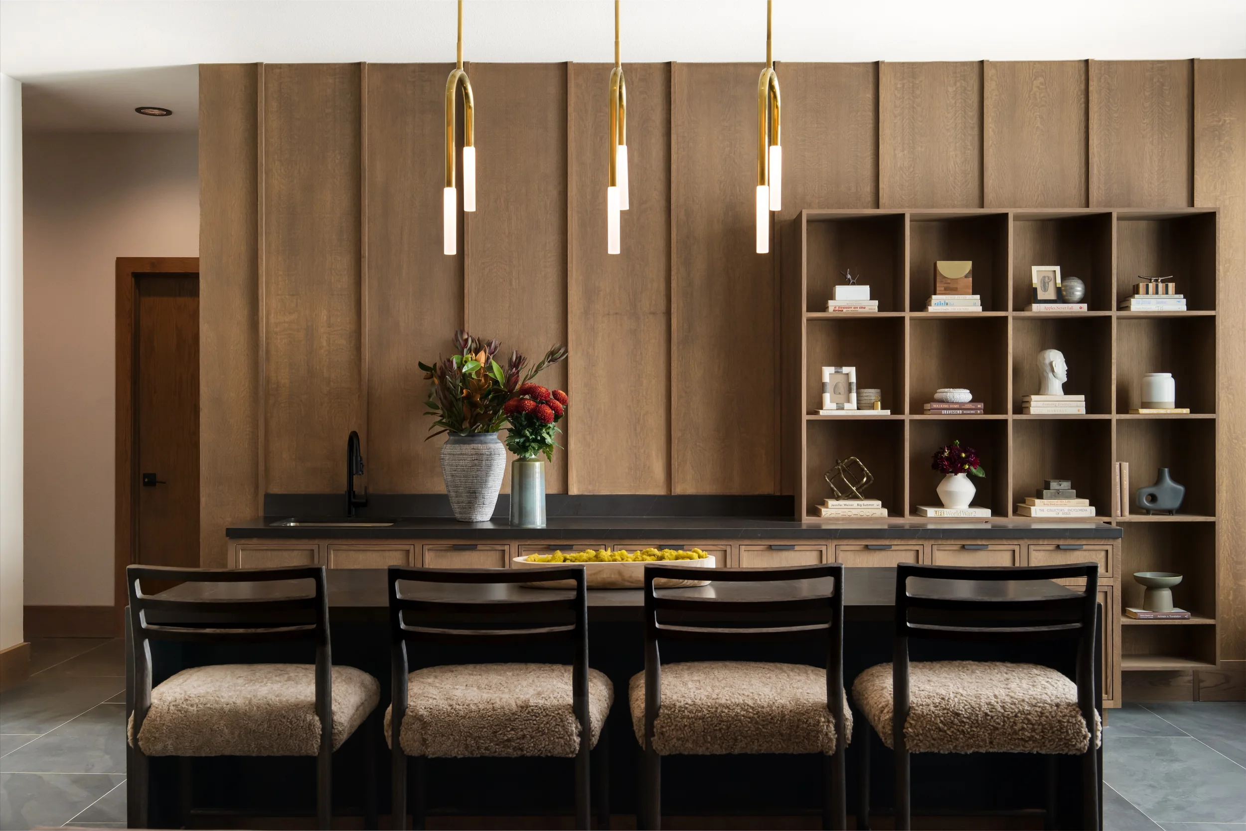 Oak-paneled amenity bar at The View in Frisco's Rail District with brass pendants and shearling-seat stools. Designed by Artbuckle & Co.