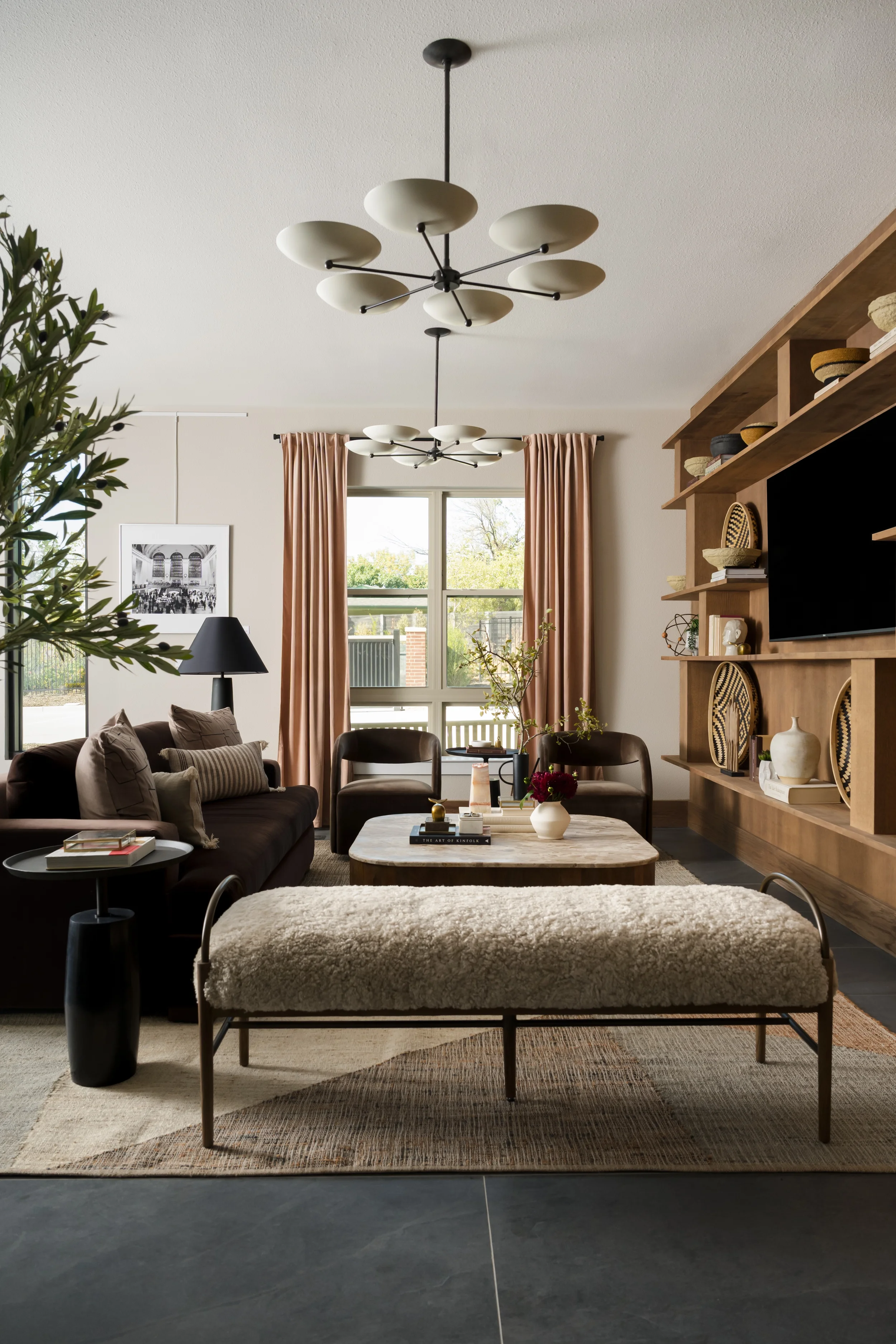 Lobby at The View in Frisco, Texas, with a walnut media wall, a shearling bench, a dark velvet sofa, and a sculptural chandelier, interior design by Artbuckle & Co.