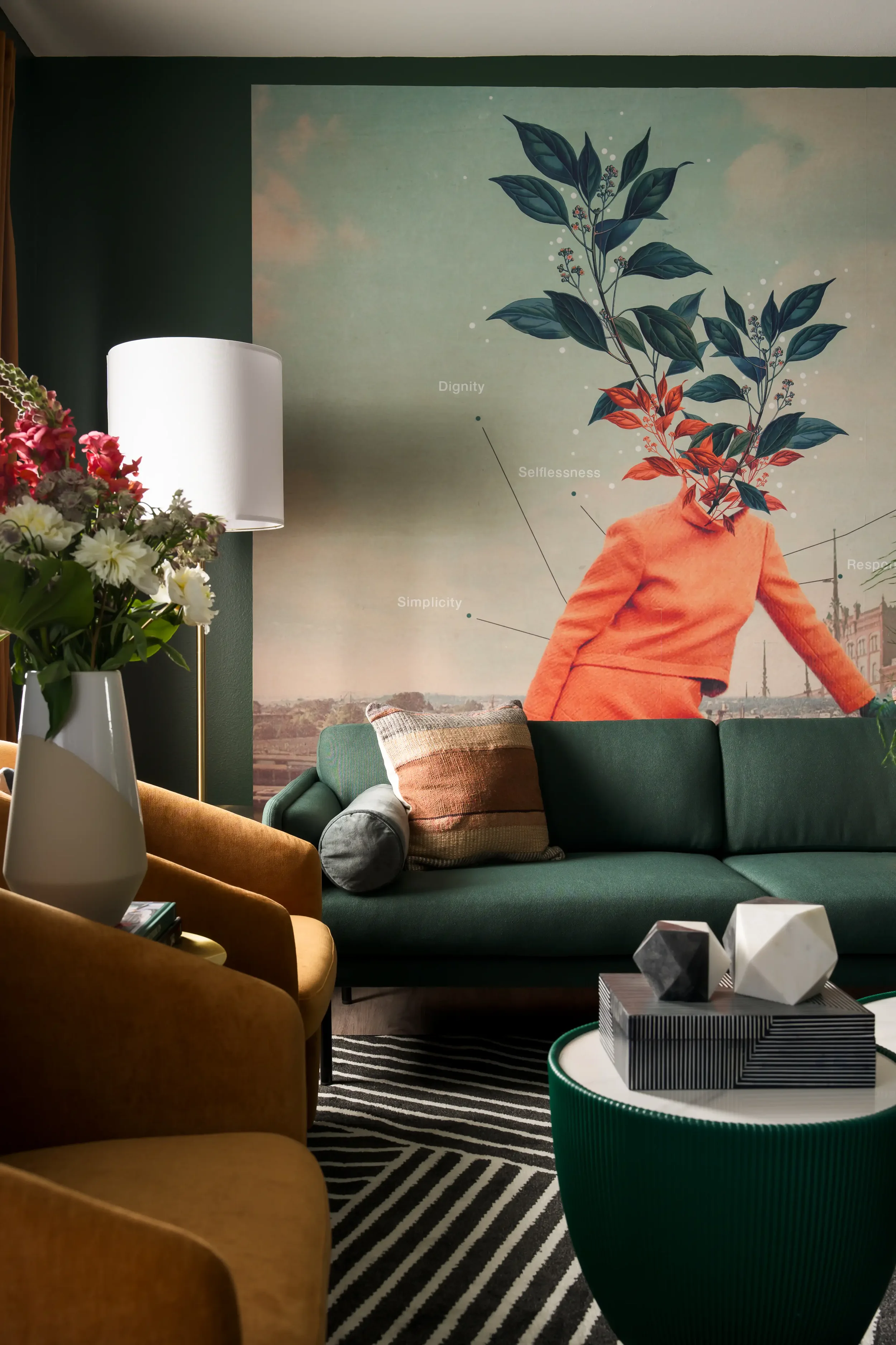 Living room with green couch, orange armchair, floral arrangement, and large wall mural featuring a person with leaves for a head and words like 'Dignity' and 'Selflessness'. Located in Dallas, T