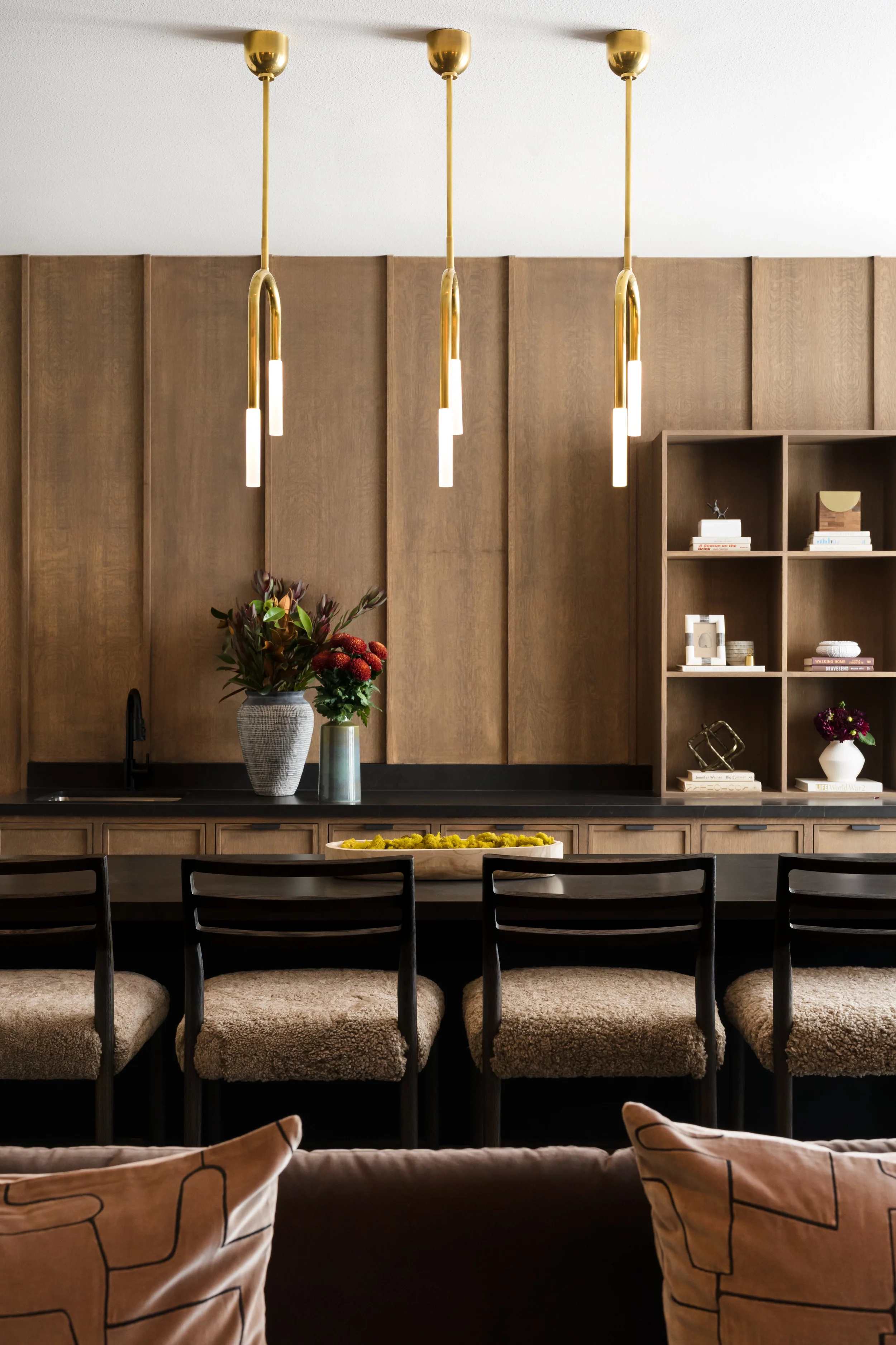 Amenity station at The View in Frisco, Texas, with walnut wall paneling, brass pendant lights, and shearling bar stools, interior design by Artbuckle & Co.