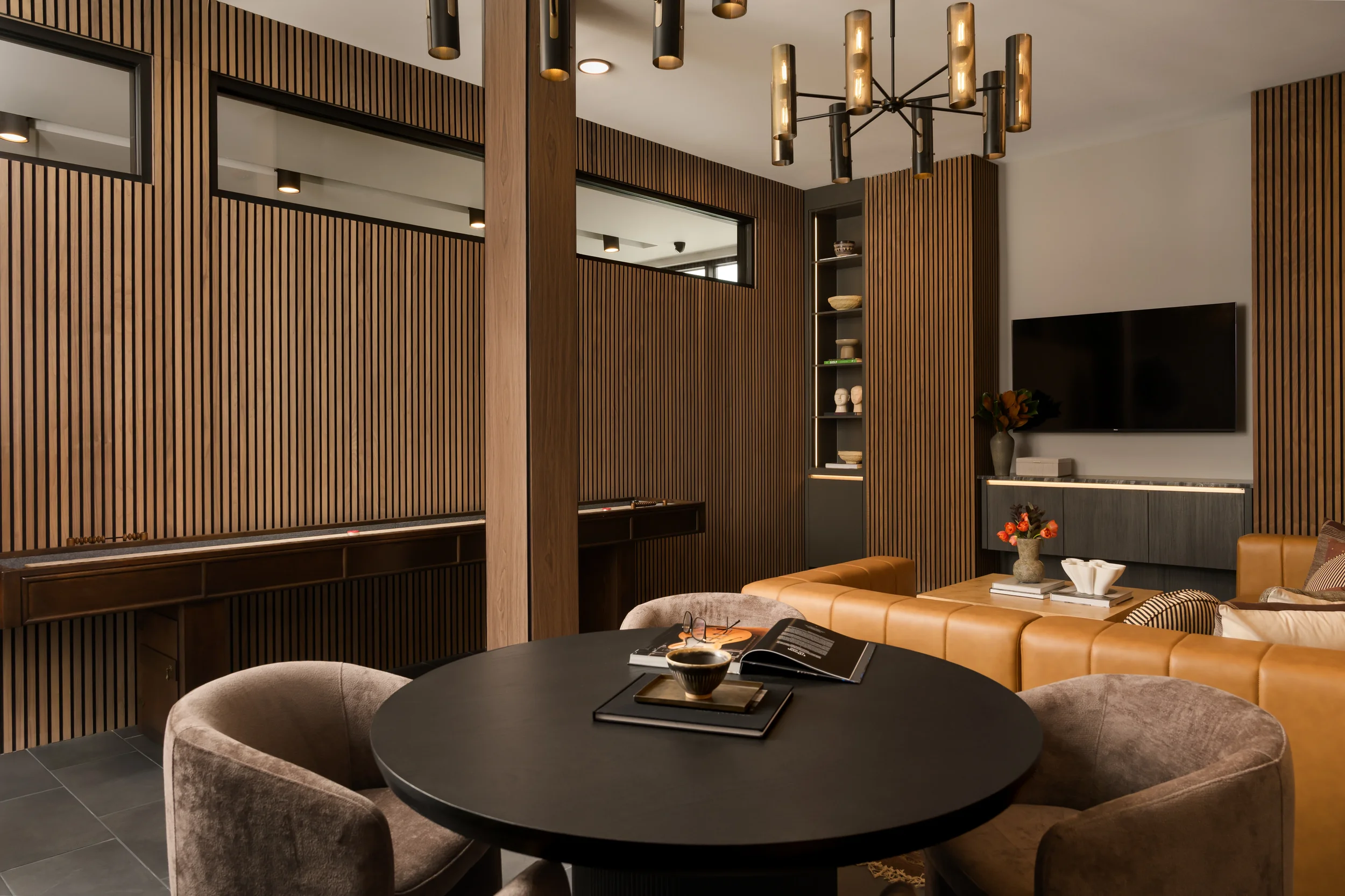 Lounge at The Platform in Frisco, TX with black round table, leather sectional and fluted walnut walls. Designed by Artbuckle & Co.