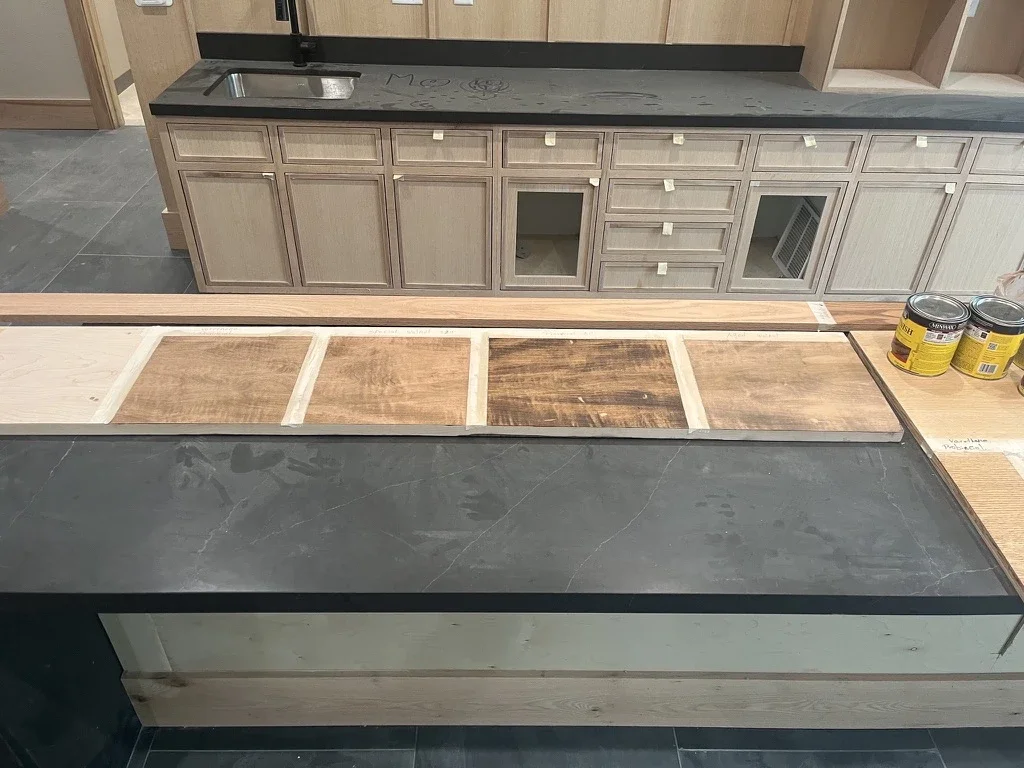 Oak cabinetry with stain test patches on the countertop edge at The View in Frisco's Rail District. Designed by Artbuckle & Co.
