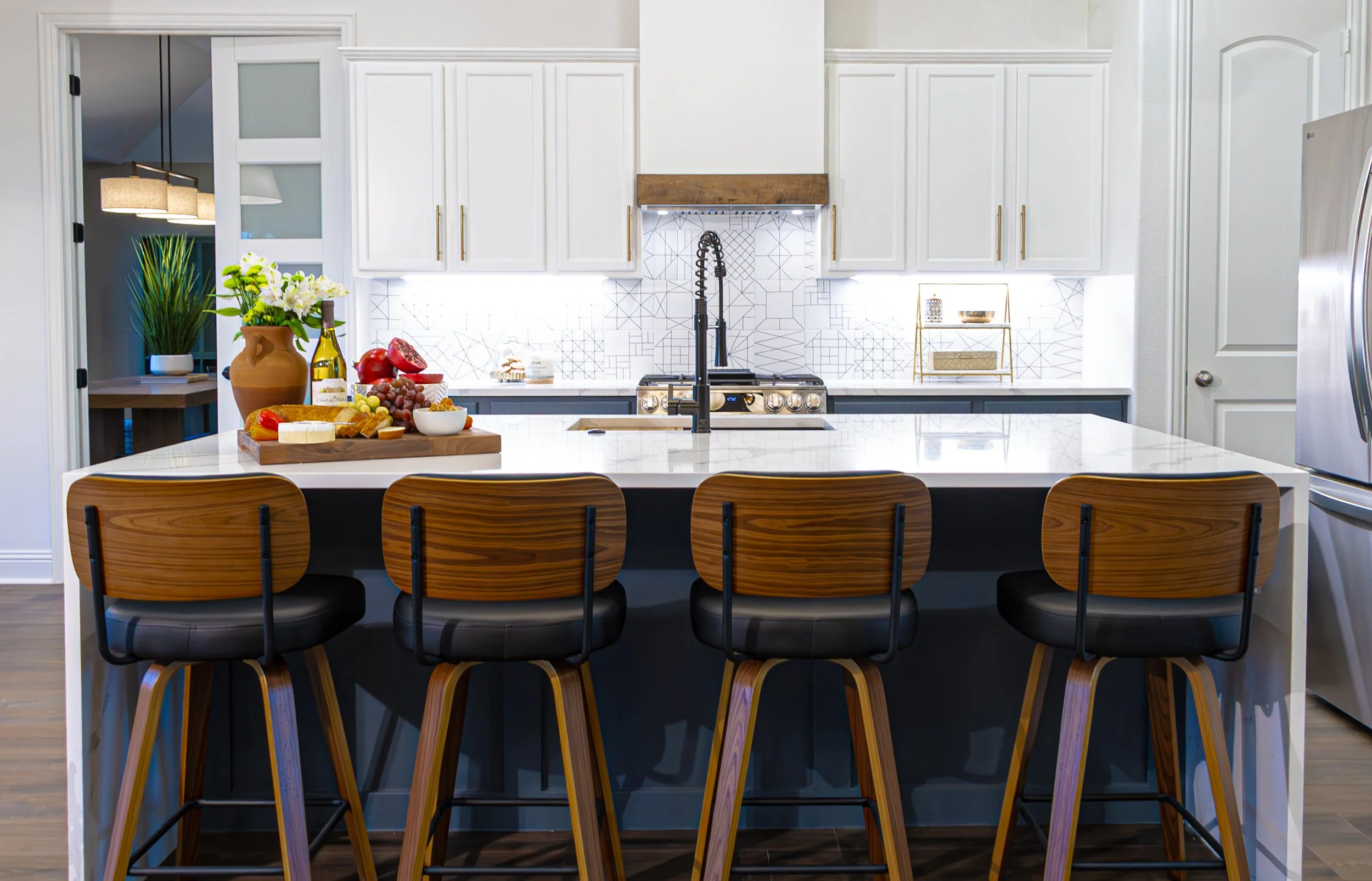 Luxury kitchen renovation in Sunnyvale, TX, featuring a custom navy island, white quartz countertops, geometric backsplash tile, and wood counter stools, designed by Artbuckle & Co.
