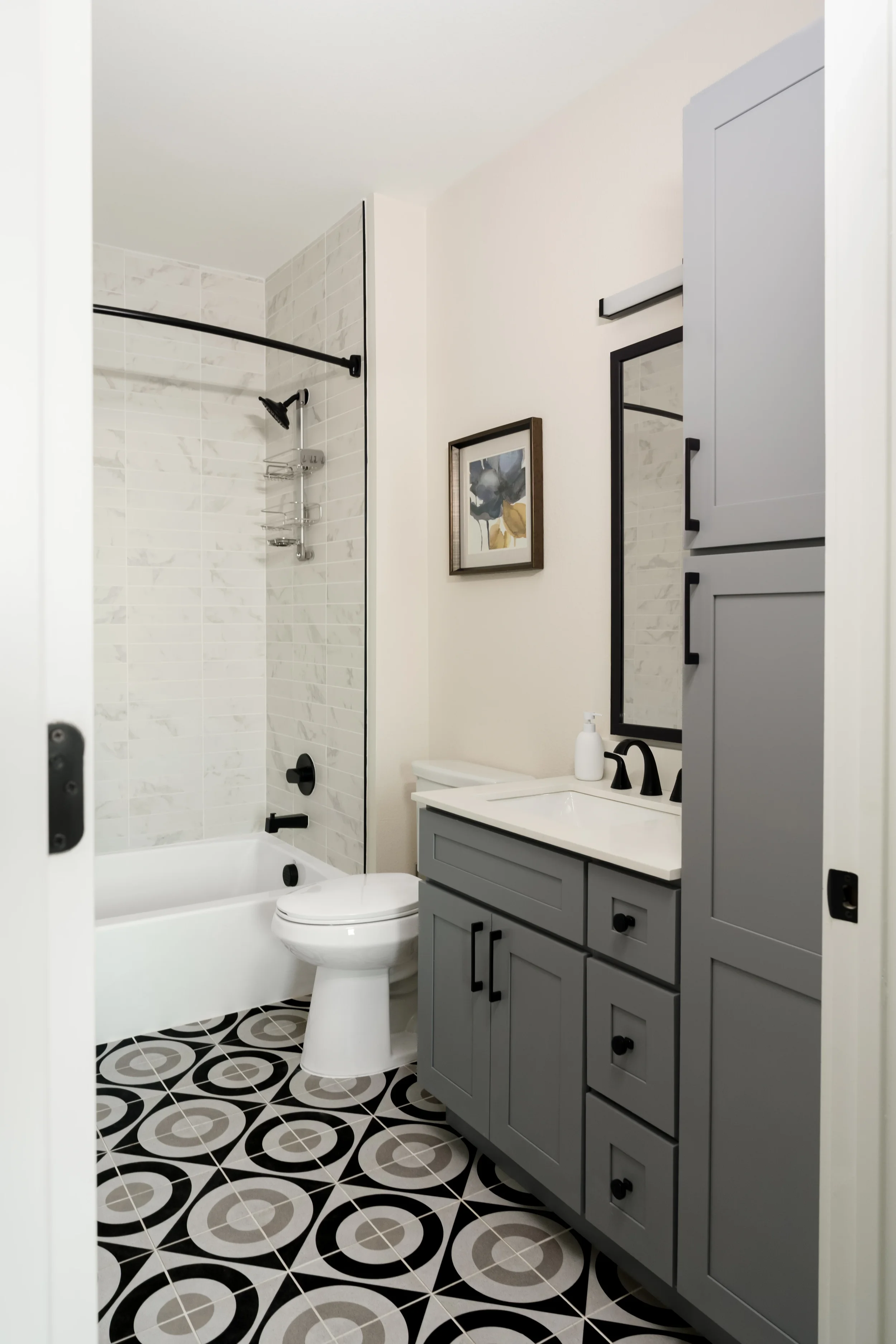 Apartment bathroom at The View in Frisco's Rail District with tub shower and graphic cement tile floor. Designed by Artbuckle & Co.
