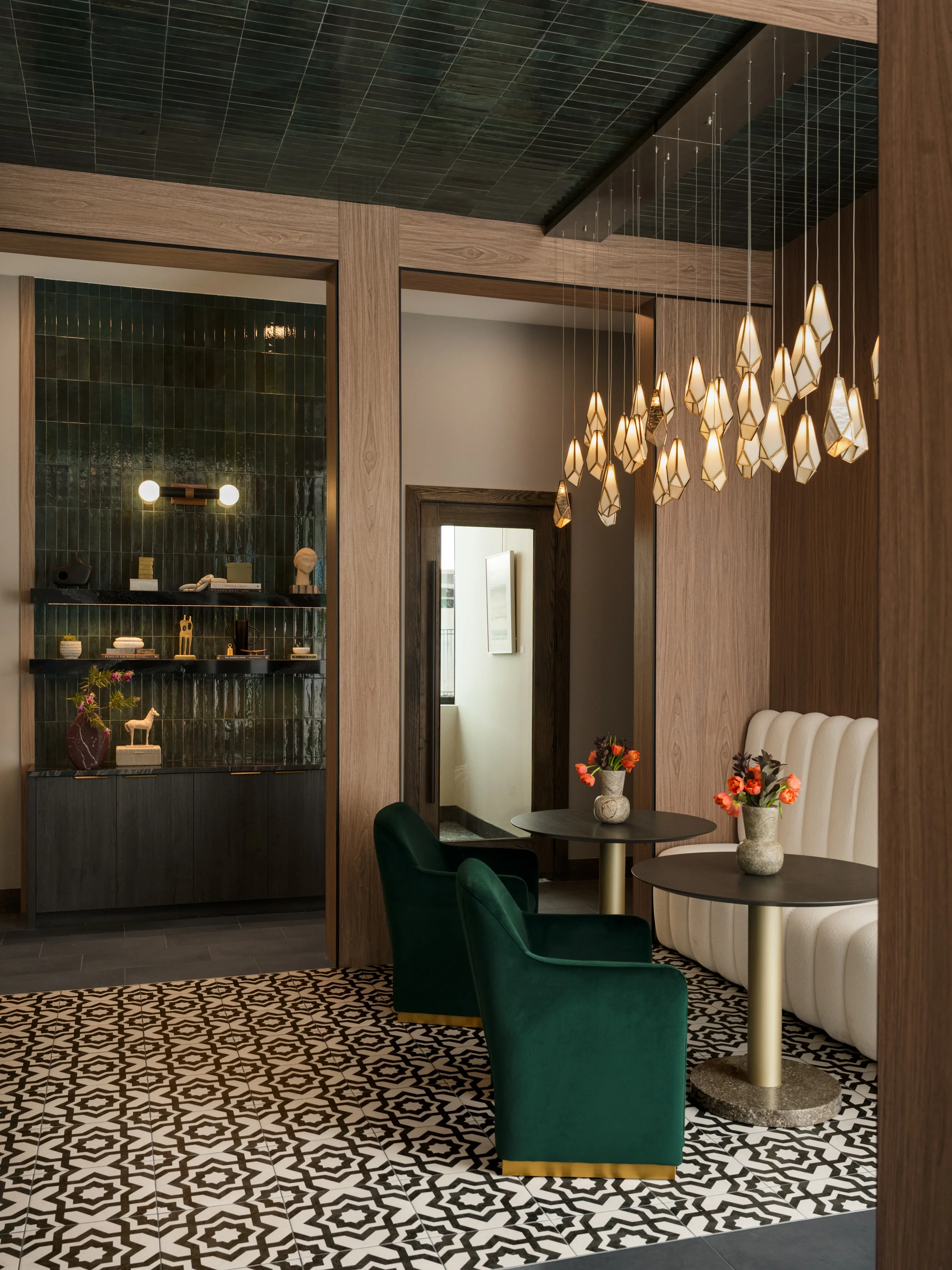 Lounge at The Platform in Frisco, Texas, with green zellige tile shelving, walnut paneling, a glass pendant cluster, and a channel-tufted banquette, designed by Artbuckle & Co.