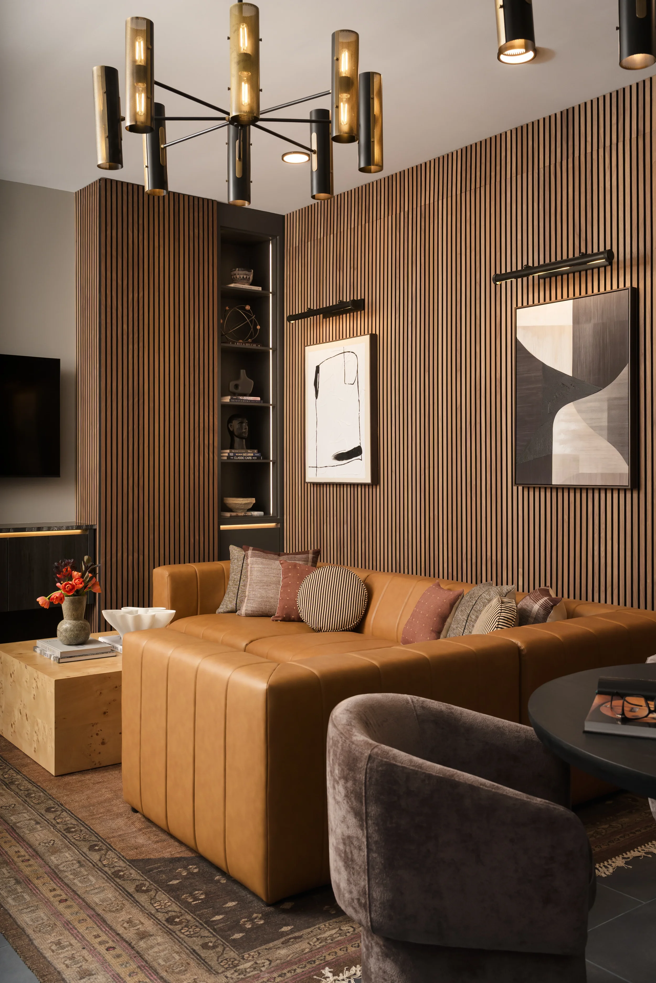 Club lounge at The Platform in Frisco, Texas, with a slatted walnut wall, a caramel leather sectional, a burl wood side table, and abstract art, designed by Artbuckle & Co.